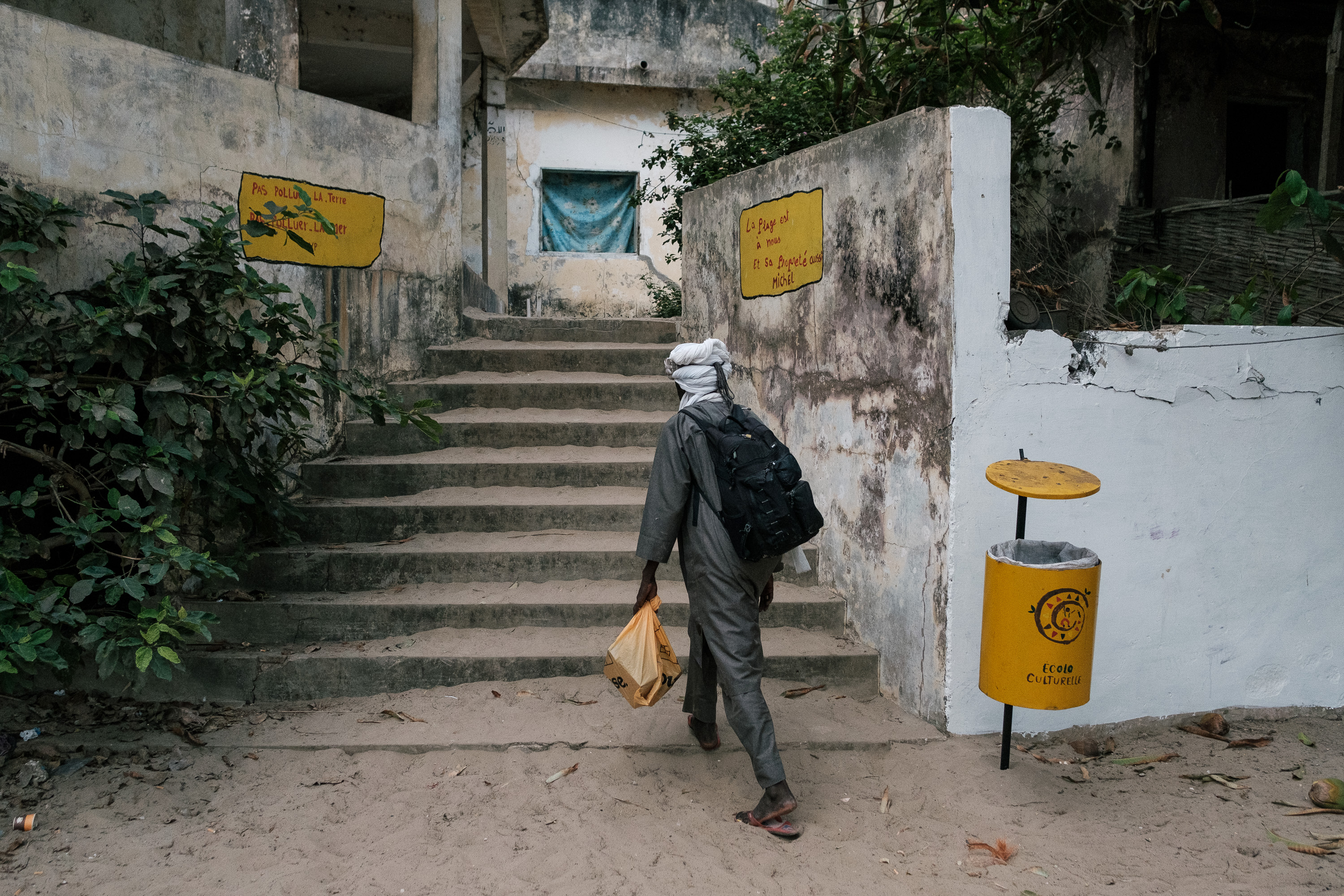 Almounzer Dicko walks back to his room up from the beach after a day of selling to tourists while carrying his jewelry in bags and boxes from Mali approaching tourists on the beach to buy his products