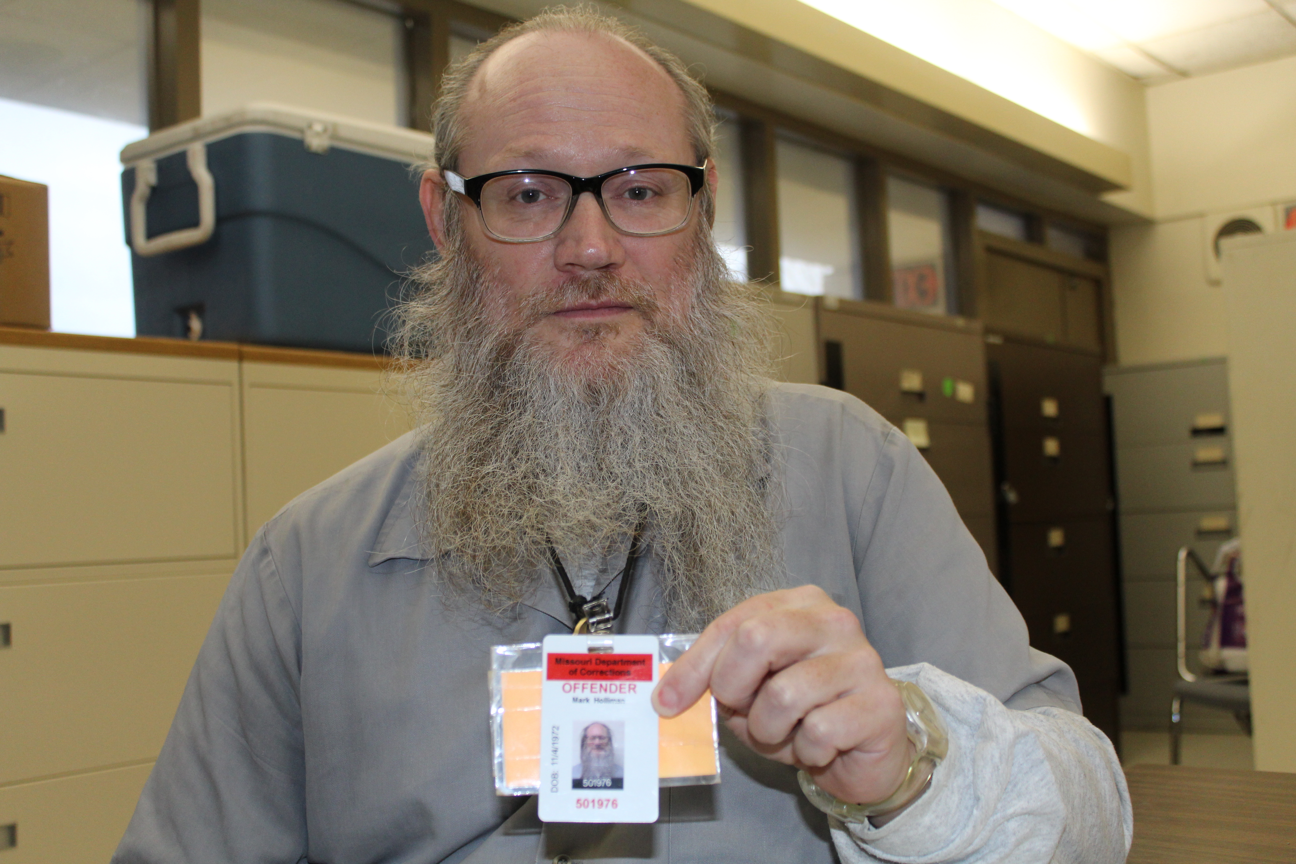 A photo of Mark (Rajul) Holliman holding up his ID card with the word 