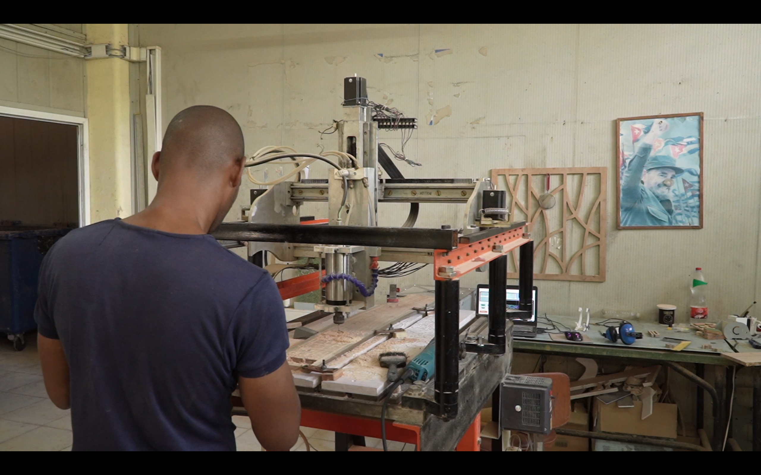 a worker oversees production of didactic toys at Rutami Toys, Havana. A portrait of Fidel Castro hangs on the wall