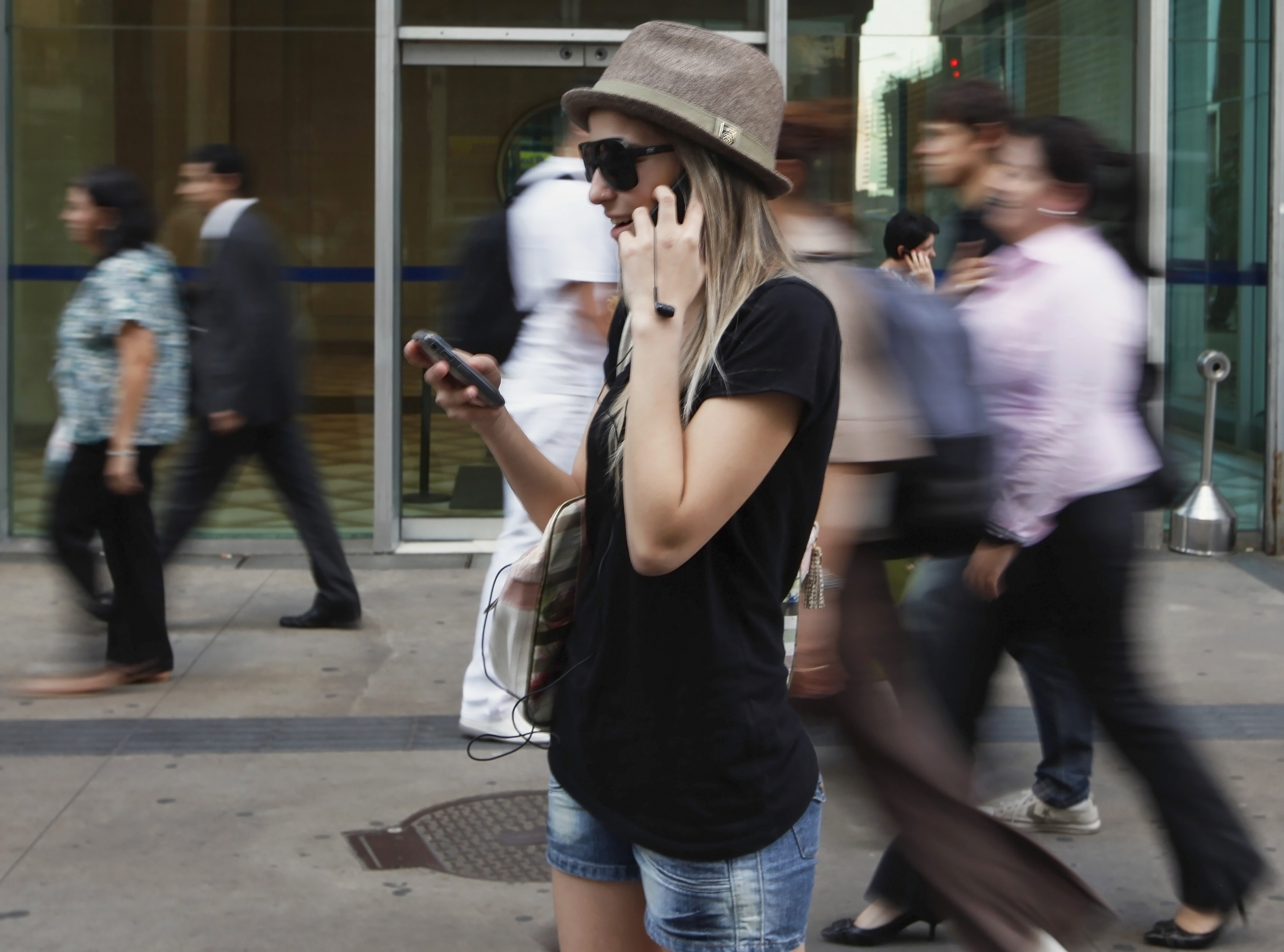 A woman uses mobile phones as she talks, writes a message and listens to music in Sao Paulo, Brazil