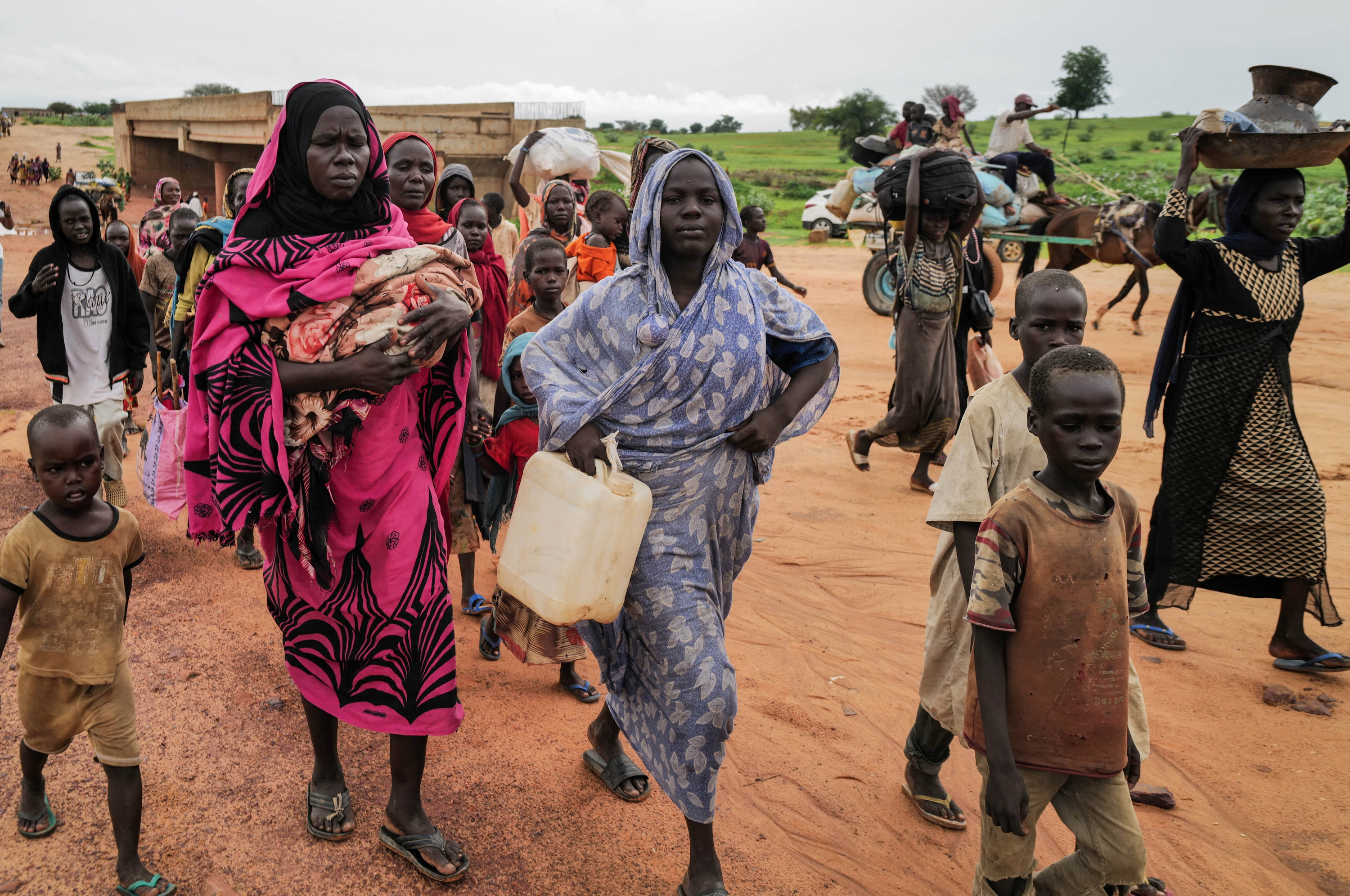 Sudanese people, who fled the conflict in Murnei in Sudan's Darfur region, walk while crossing the border between Sudan and Chad in Adre, Chad
