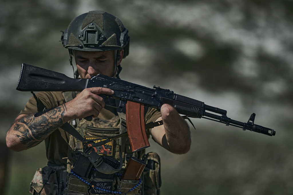 A Ukrainian soldier, code name Ara, who lost his hand a year ago in a battle with the Russian troops close to Bakhmut, holds his machine gun at the front line near Bakhmut, Donetsk region, Ukraine, Tuesday, Aug. 15, 2023. (AP Photo/Libkos)