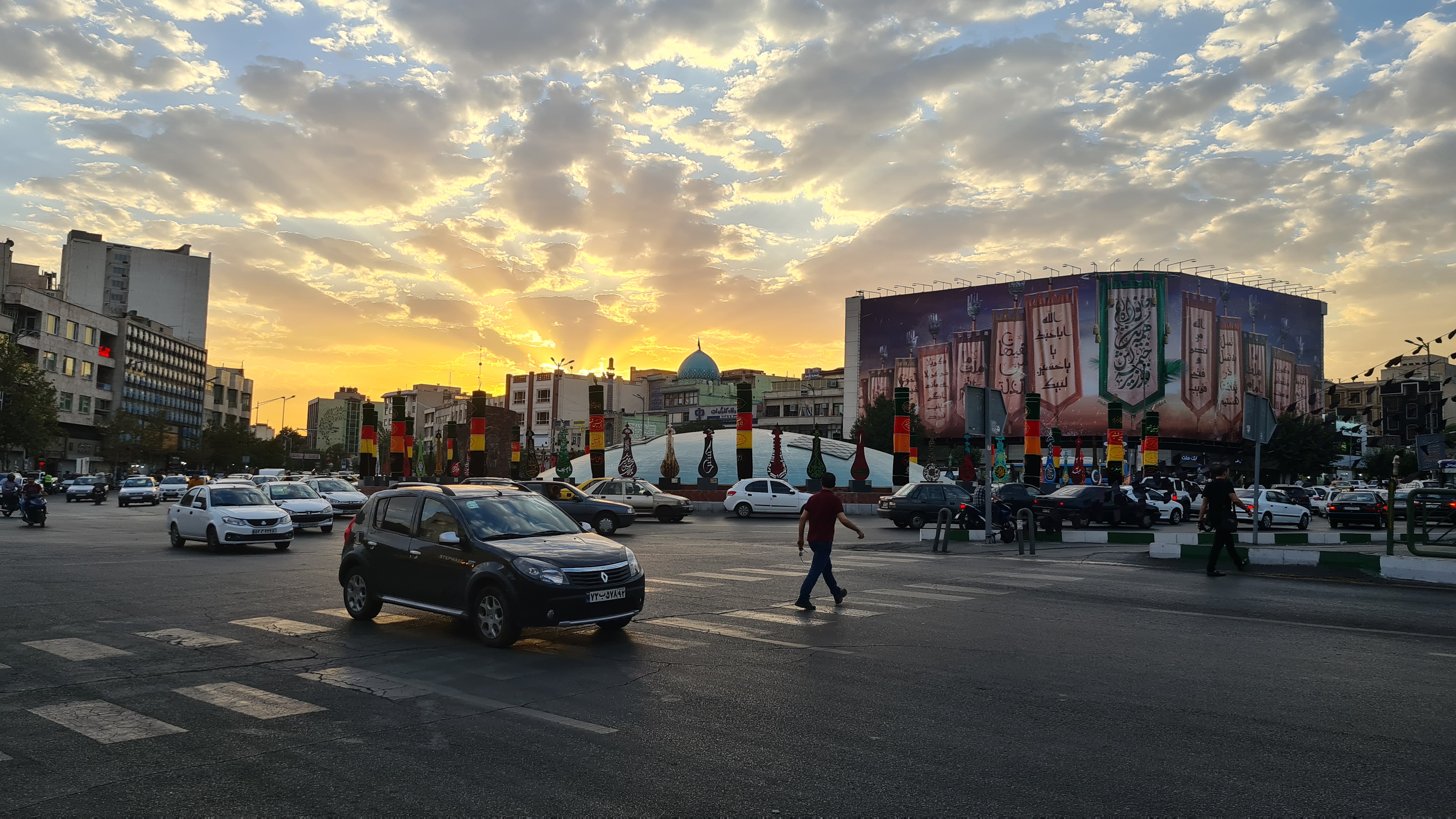 A view of a nearly deserted street in Tehran as the sun sets behind it