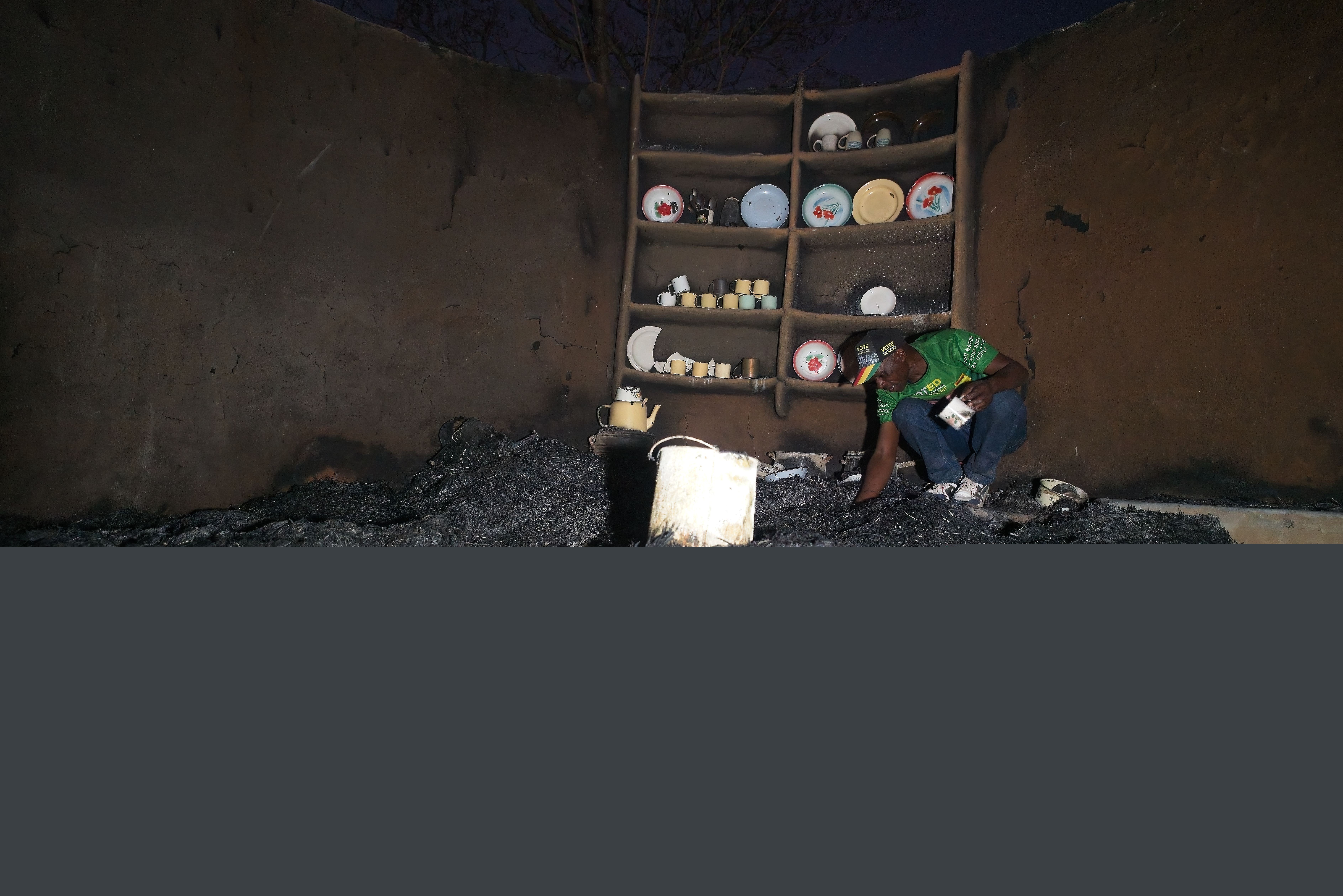 Shepherd Mahove, 48, looks through the ashes of his burnt kitchen at his homestead in Hanke B Village, Zimbabwe