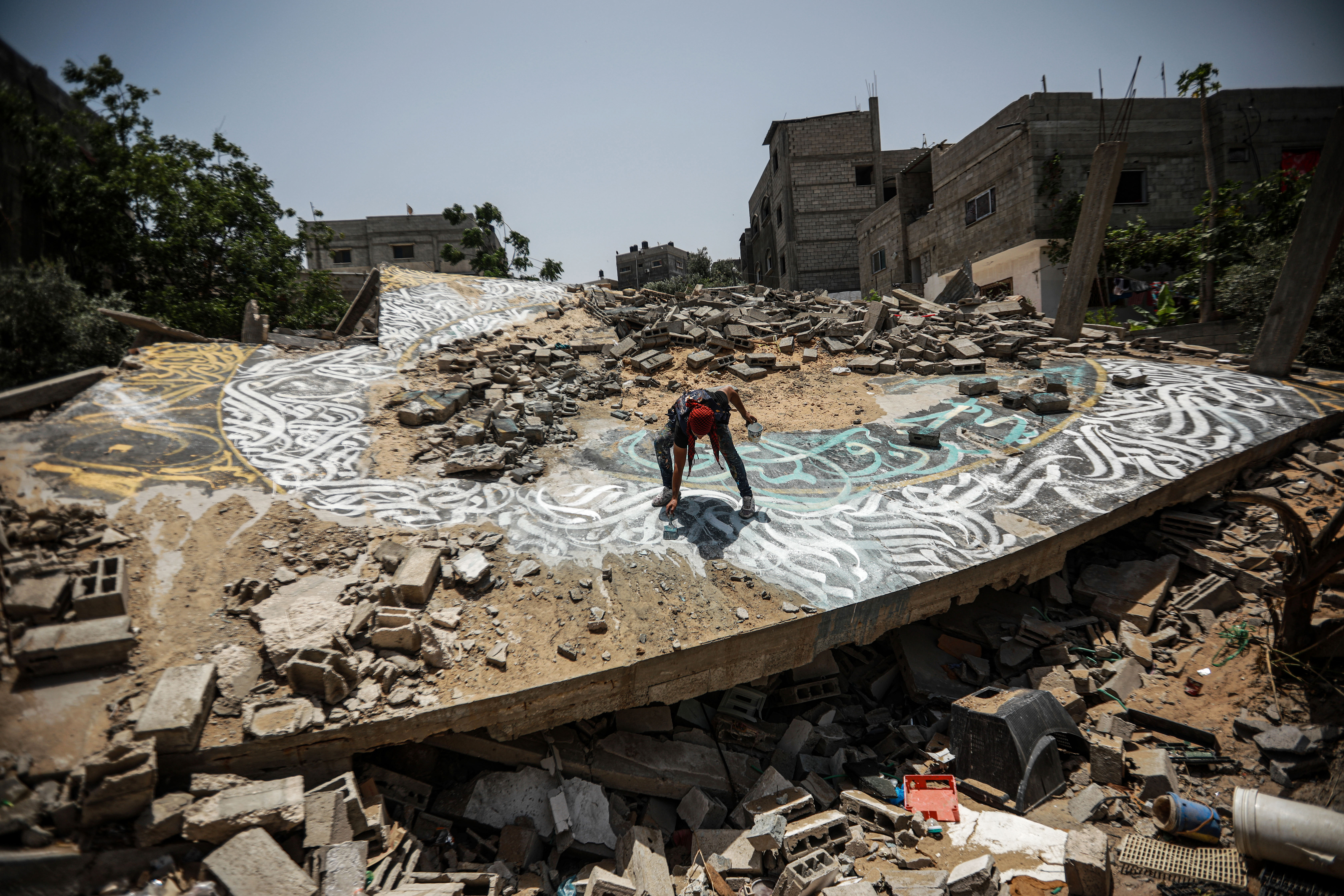 aerial shot of Ayman painting on rubble