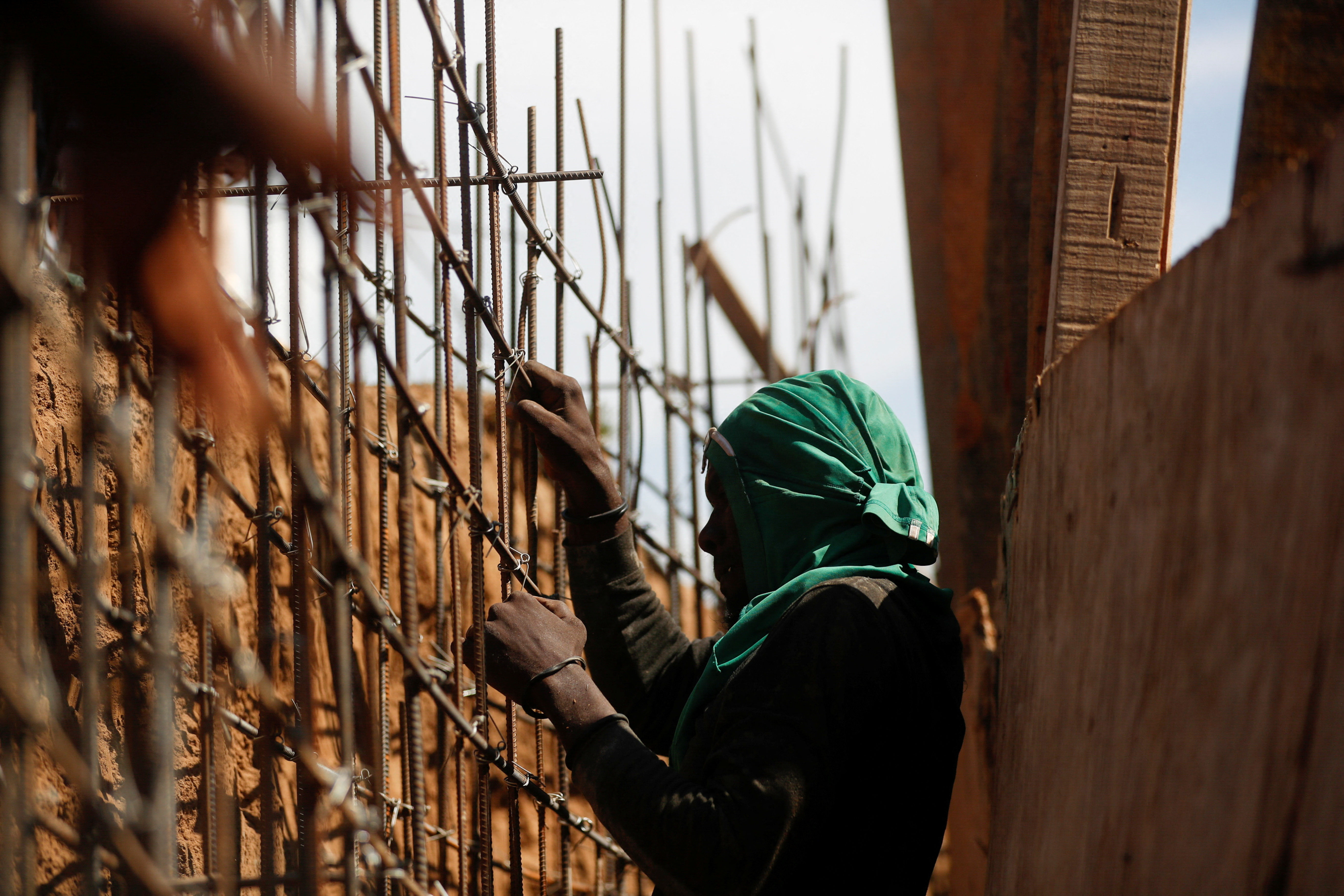 A Haitian man works on the construction site of a water channel from the Massacre river, a river shared between Haiti and the Dominican Republic, after Dominican President Luis Abinader announced a total border shutdown amid a conflict over the construction of the channel, in Ouanaminthe, Haiti September 15, 2023. With a green bandana wrapped around his head, the man weaves reeds to form a barrier in the canal. On either side of him, the outline of a channel has been developed, carved from the earth and reinforced by wooden barriers.