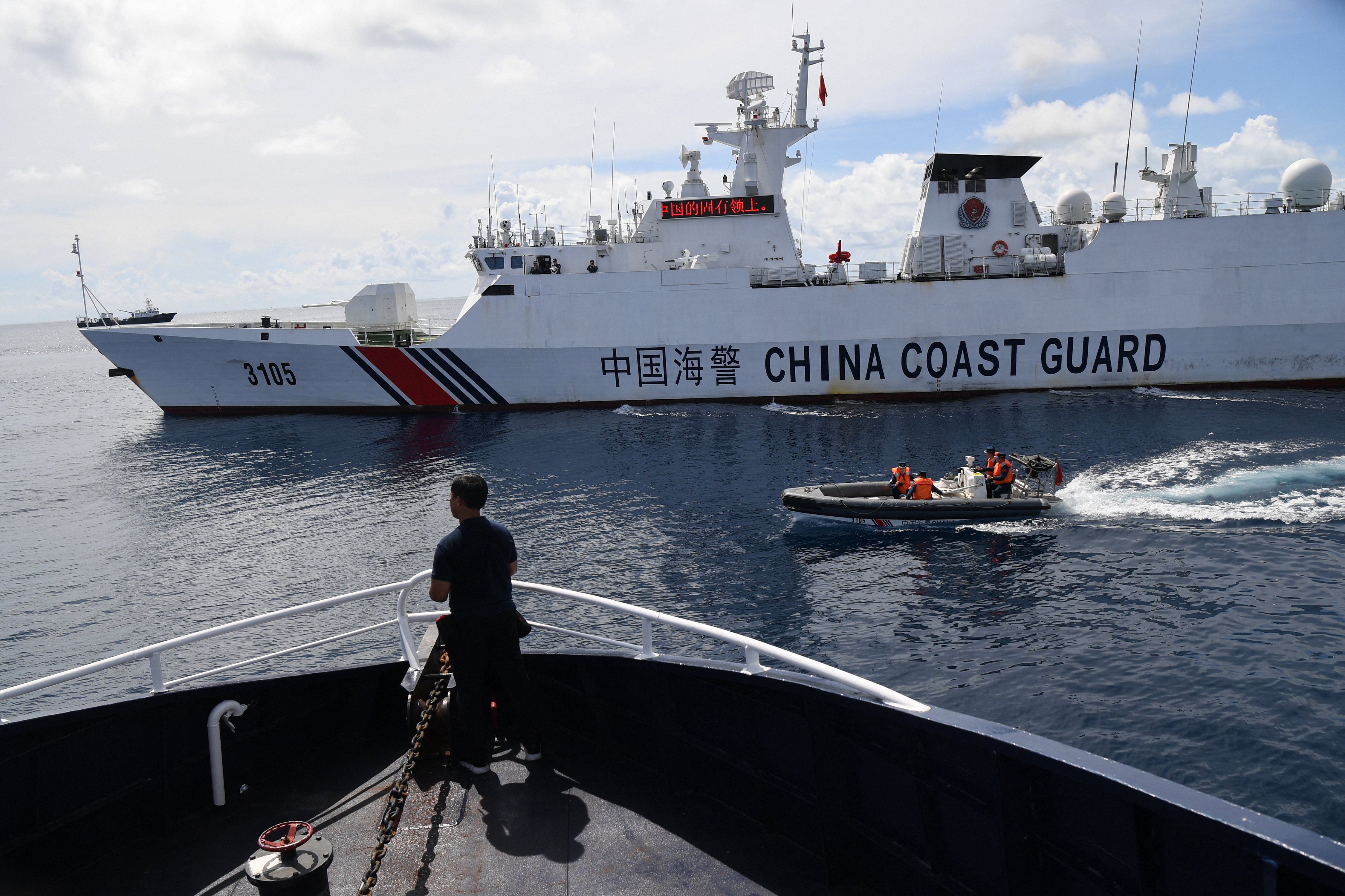 This photo taken on September 22, 2023 shows Chinese coast guard ship (R) blocking a Philippine Bureau of Fisheries and Aquatic Resources' (BFAR) ship (L) while its personnel aboard a rigid hull inflatable boat sailing past the Philippine ship as it neared the Chinese-controlled Scarborough Shoal in the disputed South China Sea. China, which claims sovereignty over almost the entire South China Sea, snatched control of Scarborough Shoal from the Philippines in 2012. Since then, it has deployed coast guard and other vessels to block or restrict access to the fishing ground that has been tapped by generations of Filipinos. (Photo by Ted ALJIBE / AFP)