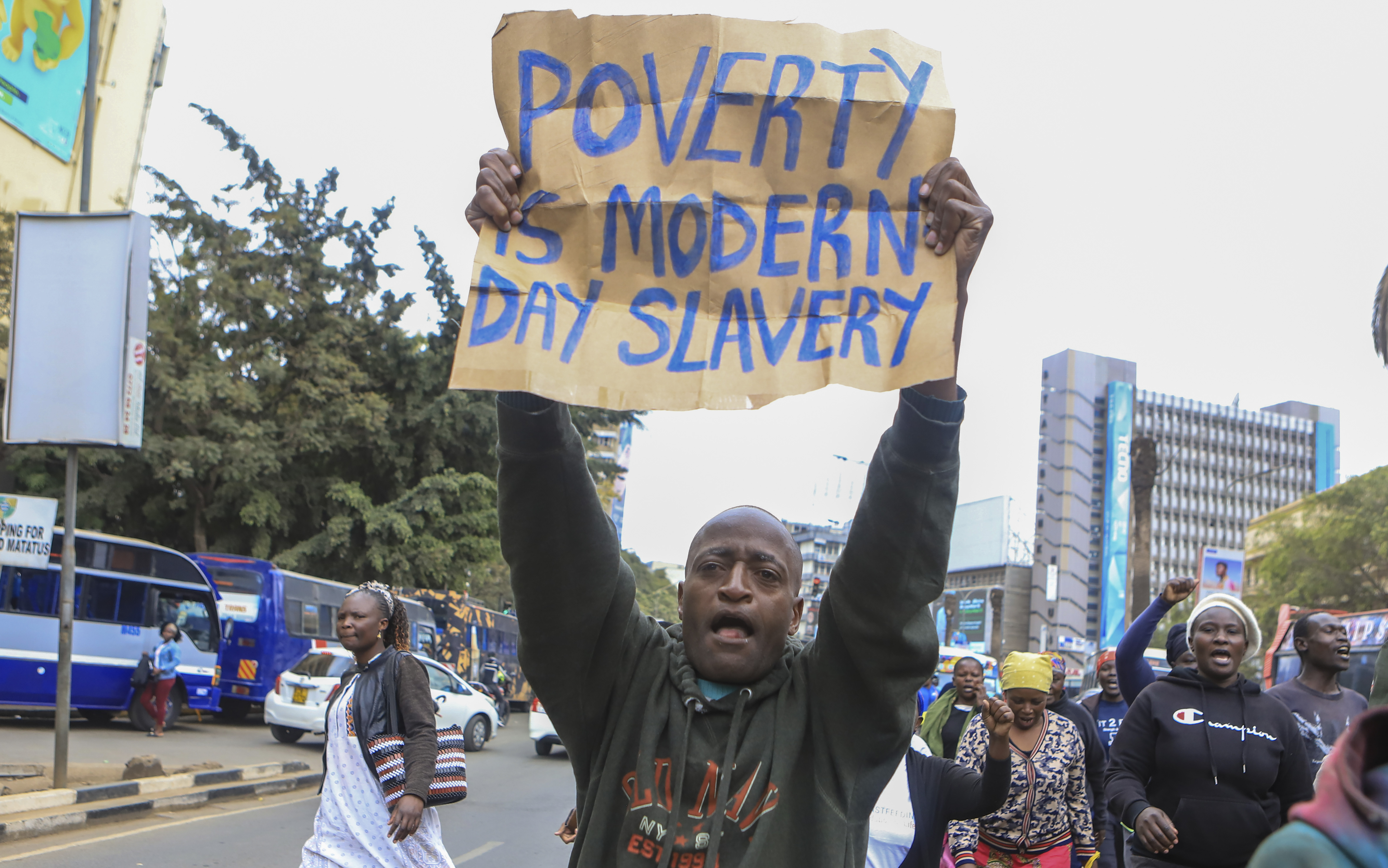 An activist holds a protest poster during a protest against high cost of living and new taxes in downtown Nairobi, Kenya