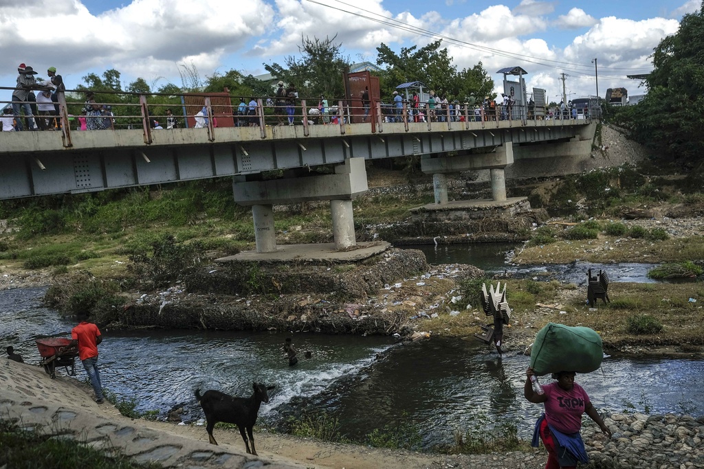 People bathe in a river below a bridge