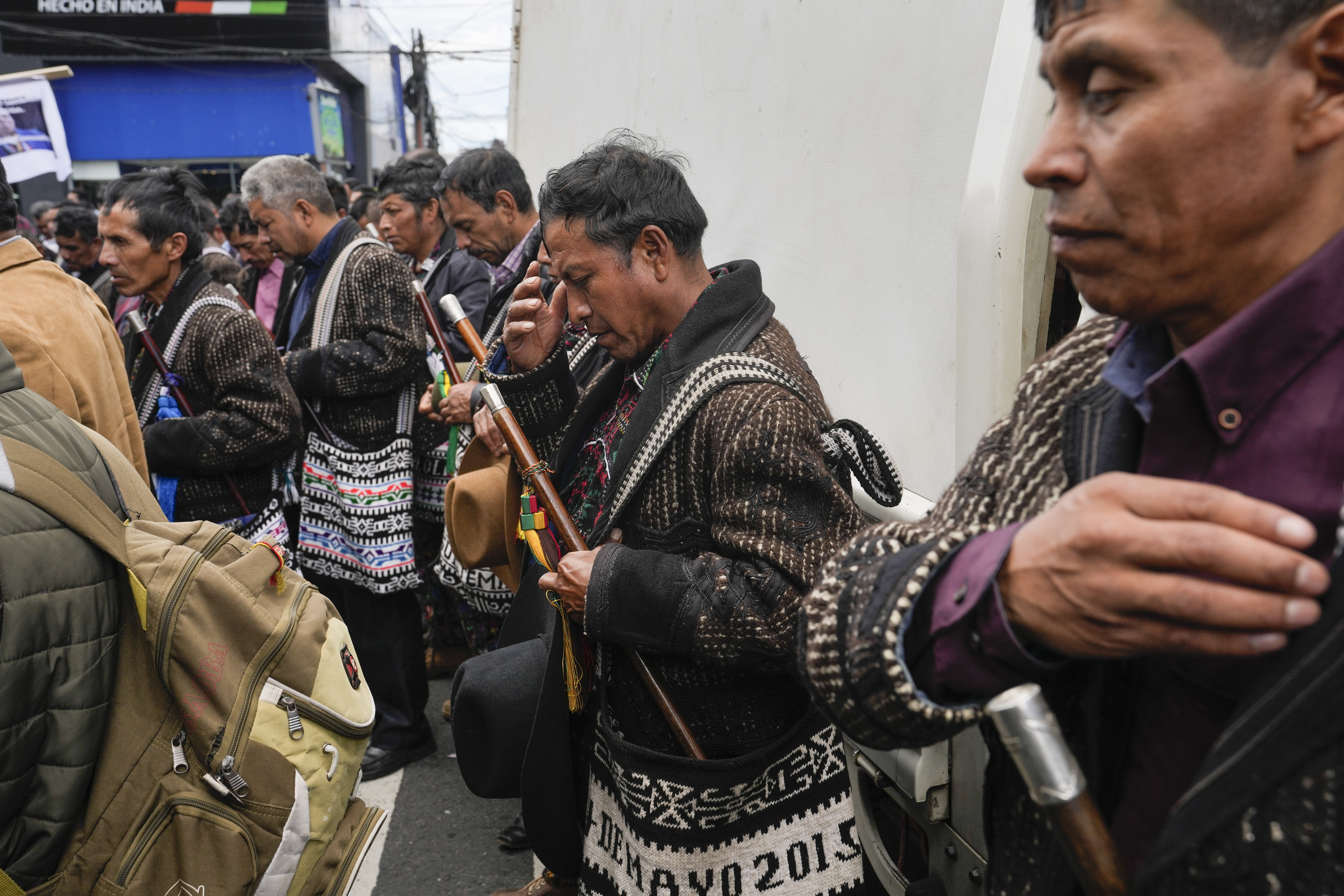 Indigenous protesters pray with eyes closed as they prepare to march in their regalia.
