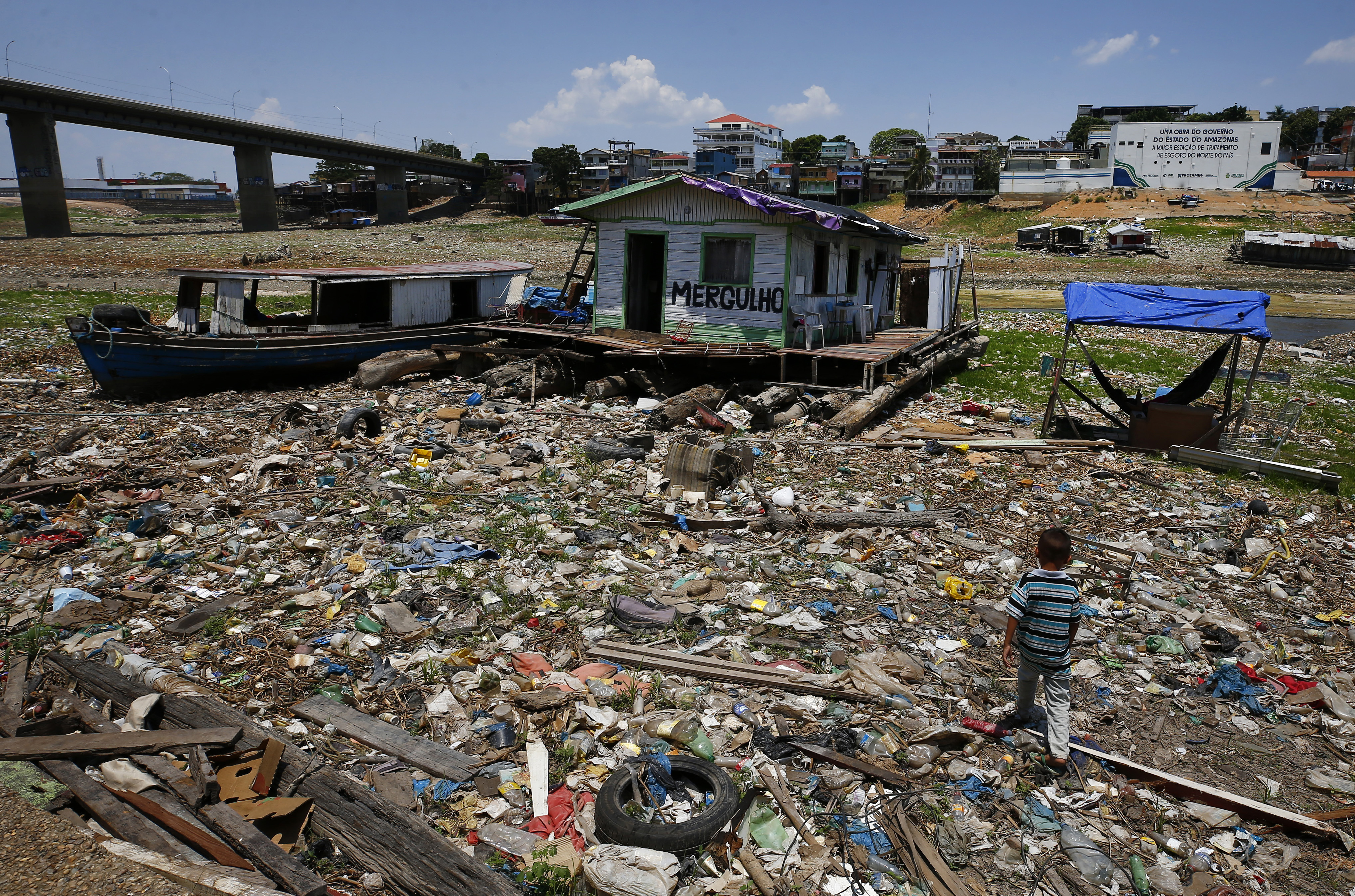 Boys walk next to a floating home stranded on what used to be the water´s edge of the Negro river,