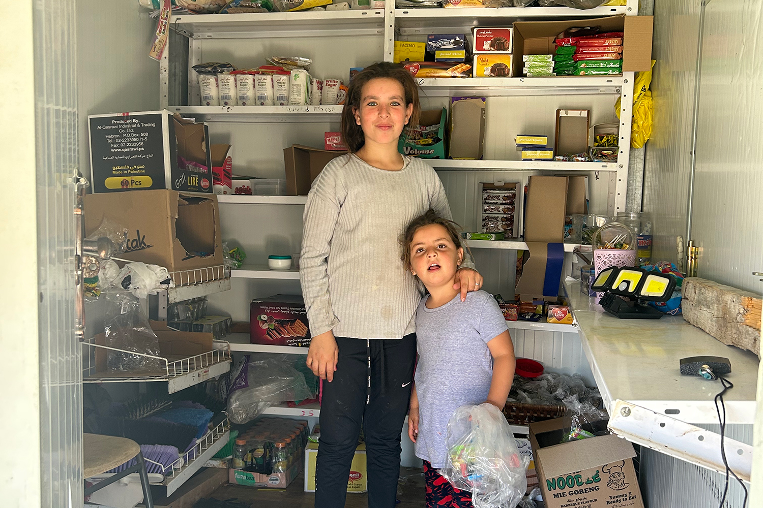 Jenan Nawajah and her sister Ritell stand inside the small shop they run, selling candies and other goodies to the other children in the village.