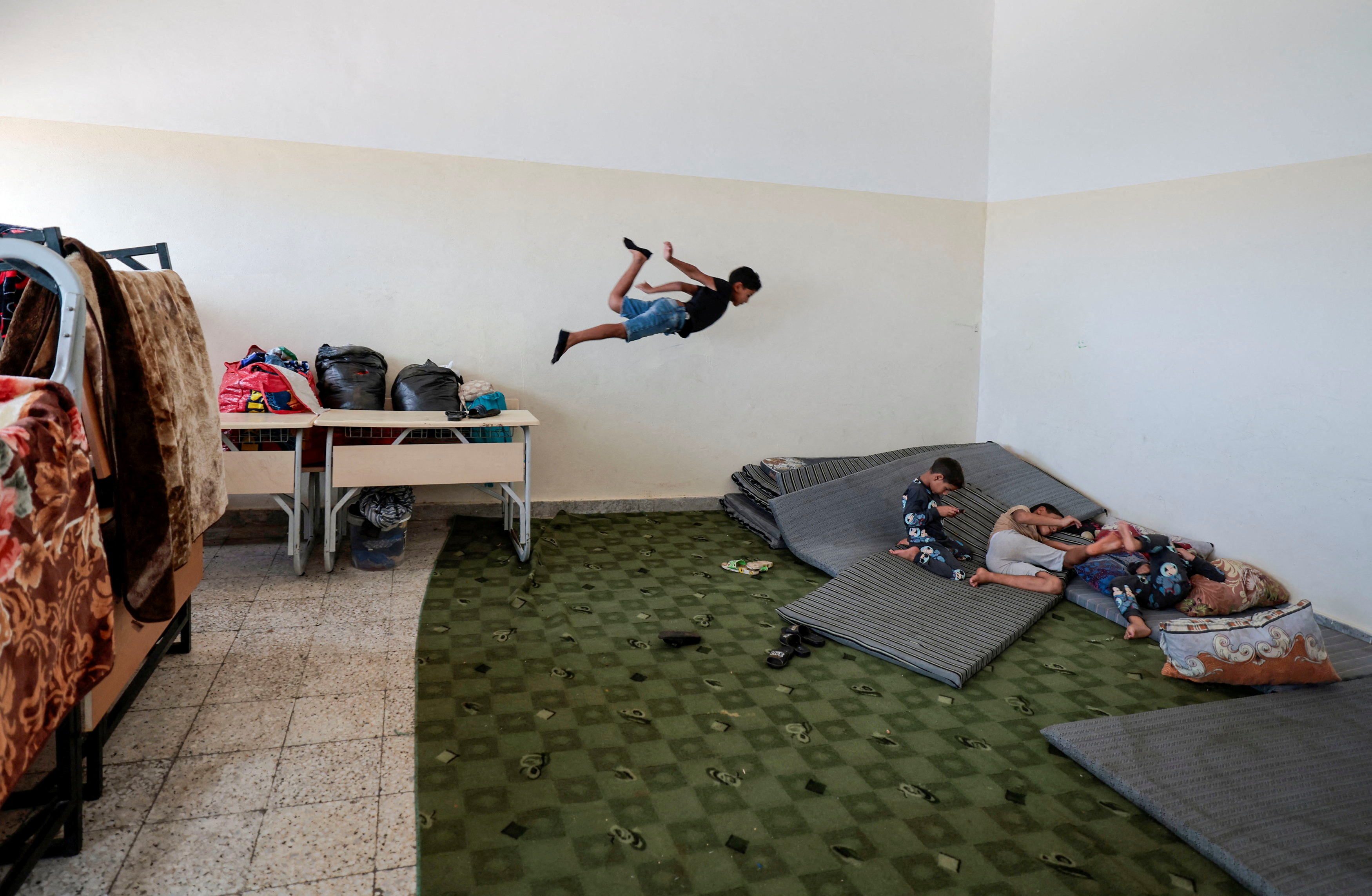 A boy, who survived the deadly storm that hit Libya, jumps as he plays with his brothers inside a classroom at Um almoumanen school, where they take shelter in Derna, Libya