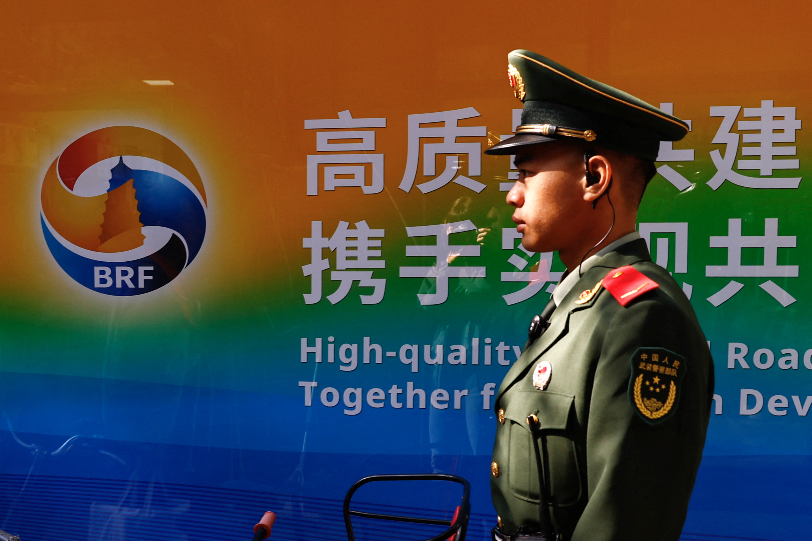 A paramilitary police officer walks past a billboard promoting the Third Belt and Road Forum