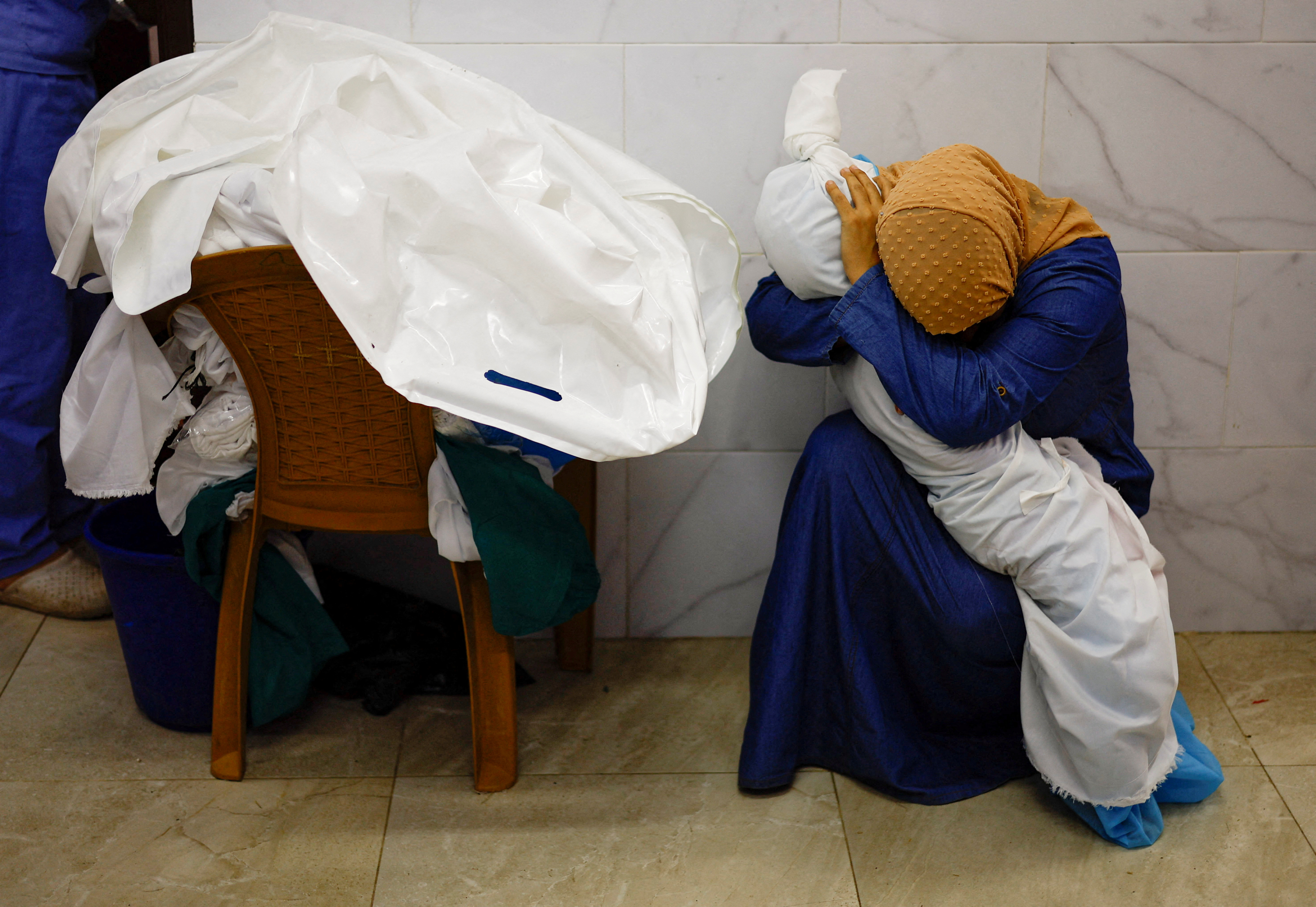 A woman embraces the body of a Palestinian child killed in Israeli strikes, at a hospital in Khan Younis