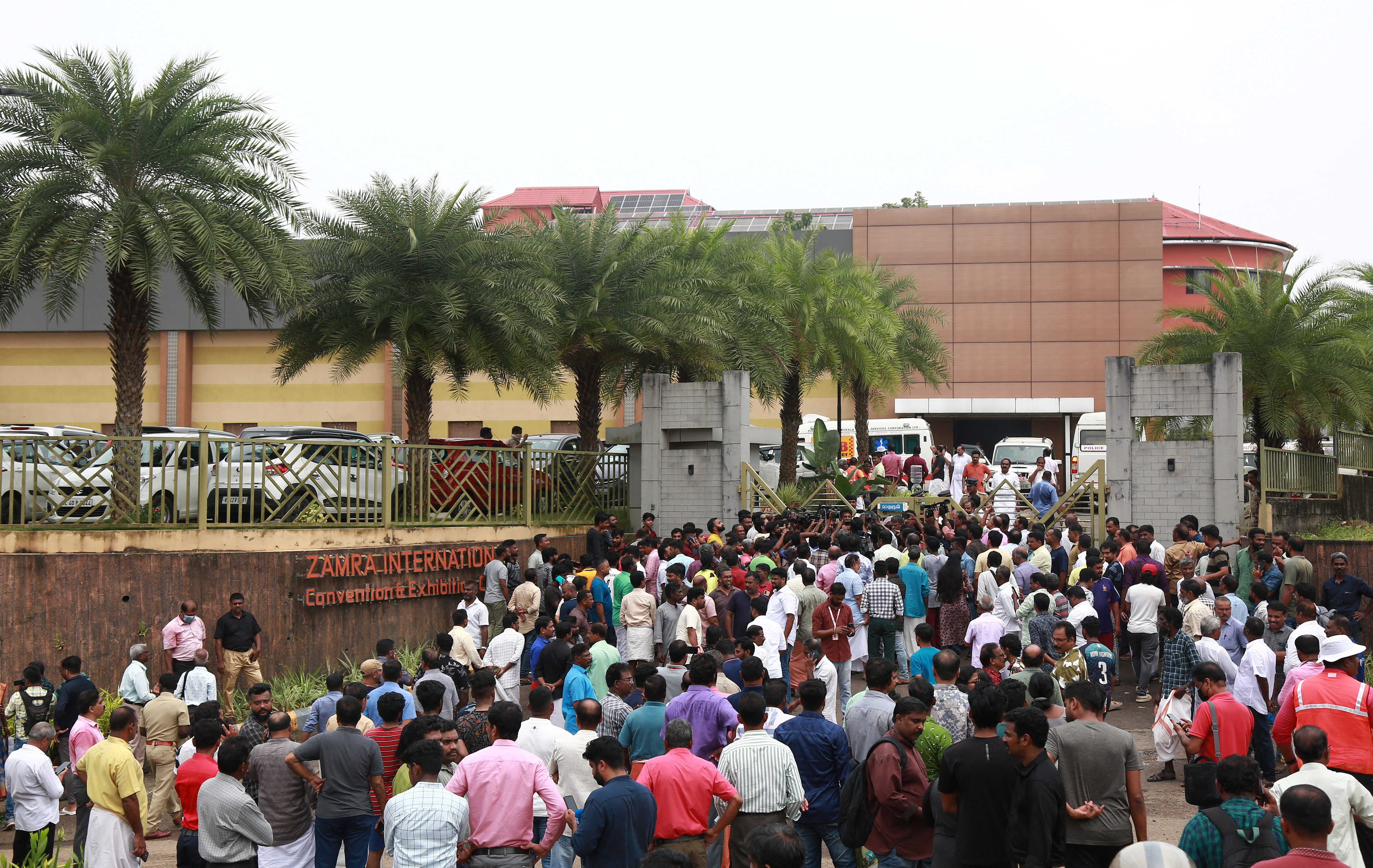 People stand outside a convention centre where multiple blasts occurred during a religious gathering in Kochi, India