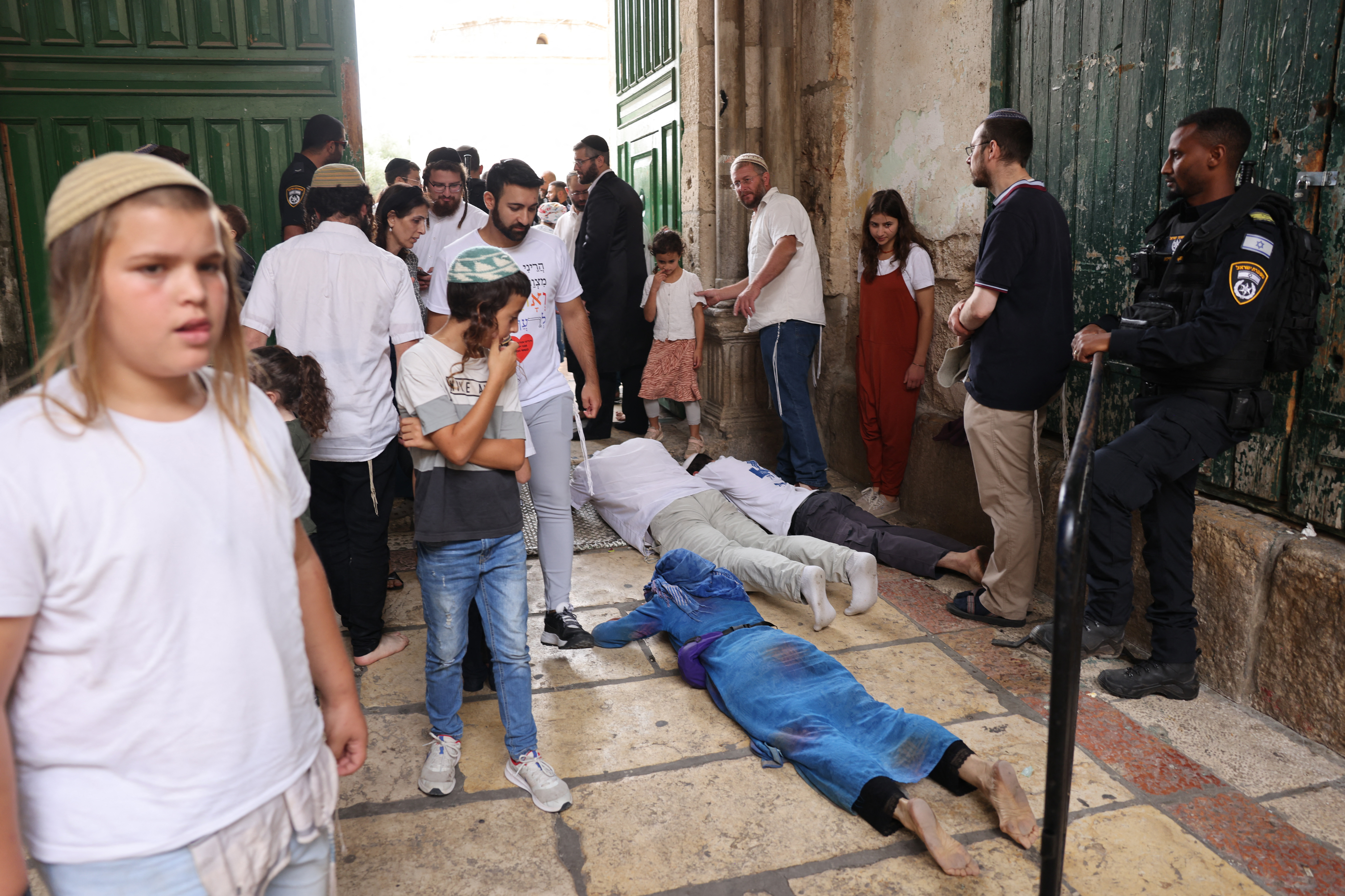 Jewish men prostrate on the ground in prayer outside the gate after a visit to the Temple Mount, known to Muslims as the Haram al-Sharif (The Noble Sanctuary), at one of the entrances of the Aqsa mosque compound in the old city of Jerusalem during the holiday of Sukkot, or the Feast of the Tabernacles, on October 2, 2023. - Thousands of Jews annually make the pilgrimage to Jerusalem during the week-long holiday of Sukkot, which commemorates the desert wanderings of the Israelites after their exodus from Egypt according to biblical tradition, and the gathering of the harvest. (Photo by Menahem KAHANA / AFP)