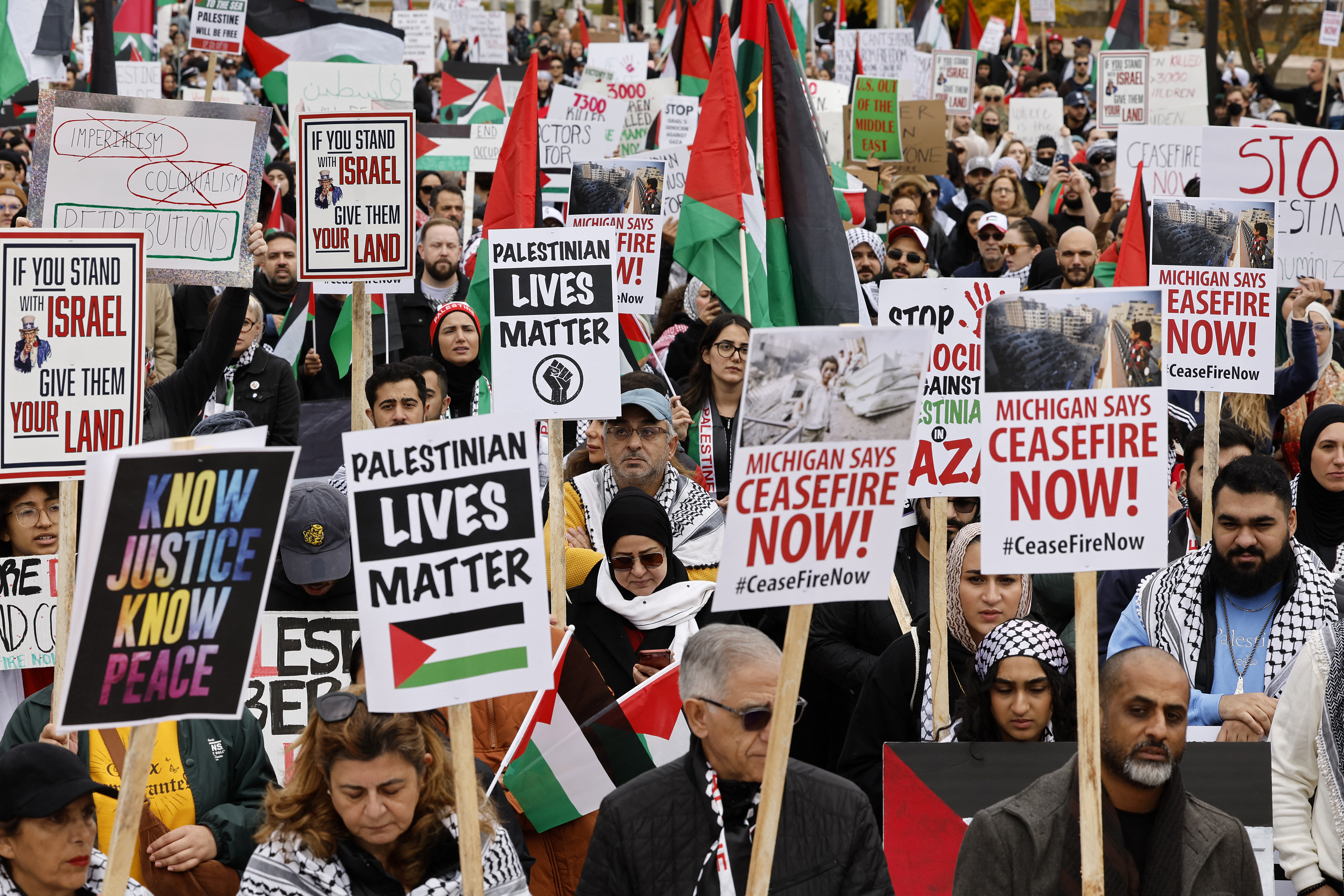 People hold signs as they gather in Hart Plaza in downtown Detroit, Michigan