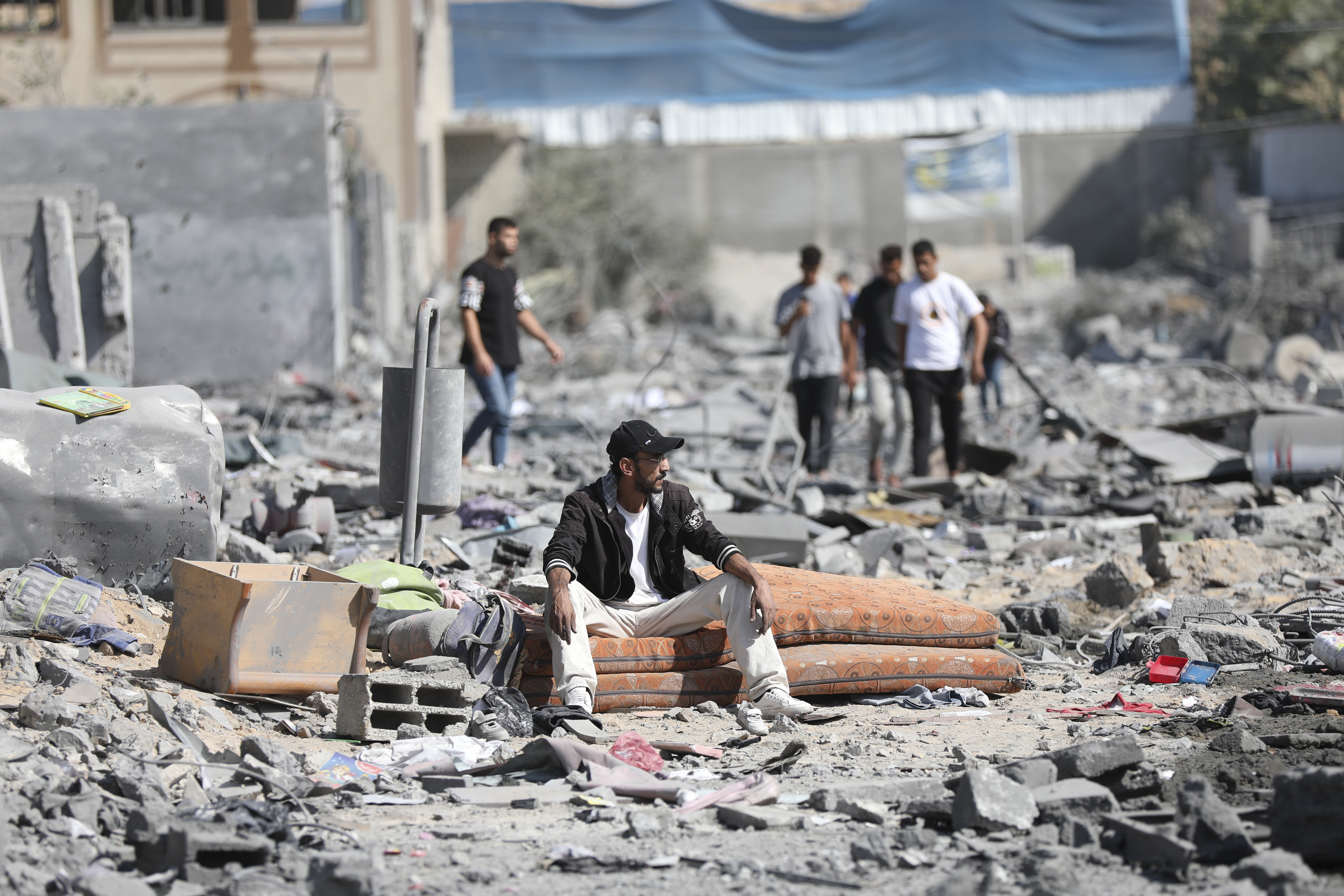 Palestinians walk by the buildings destroyed in the Israeli bombardment on al-Zahra, on the outskirts of Gaza City