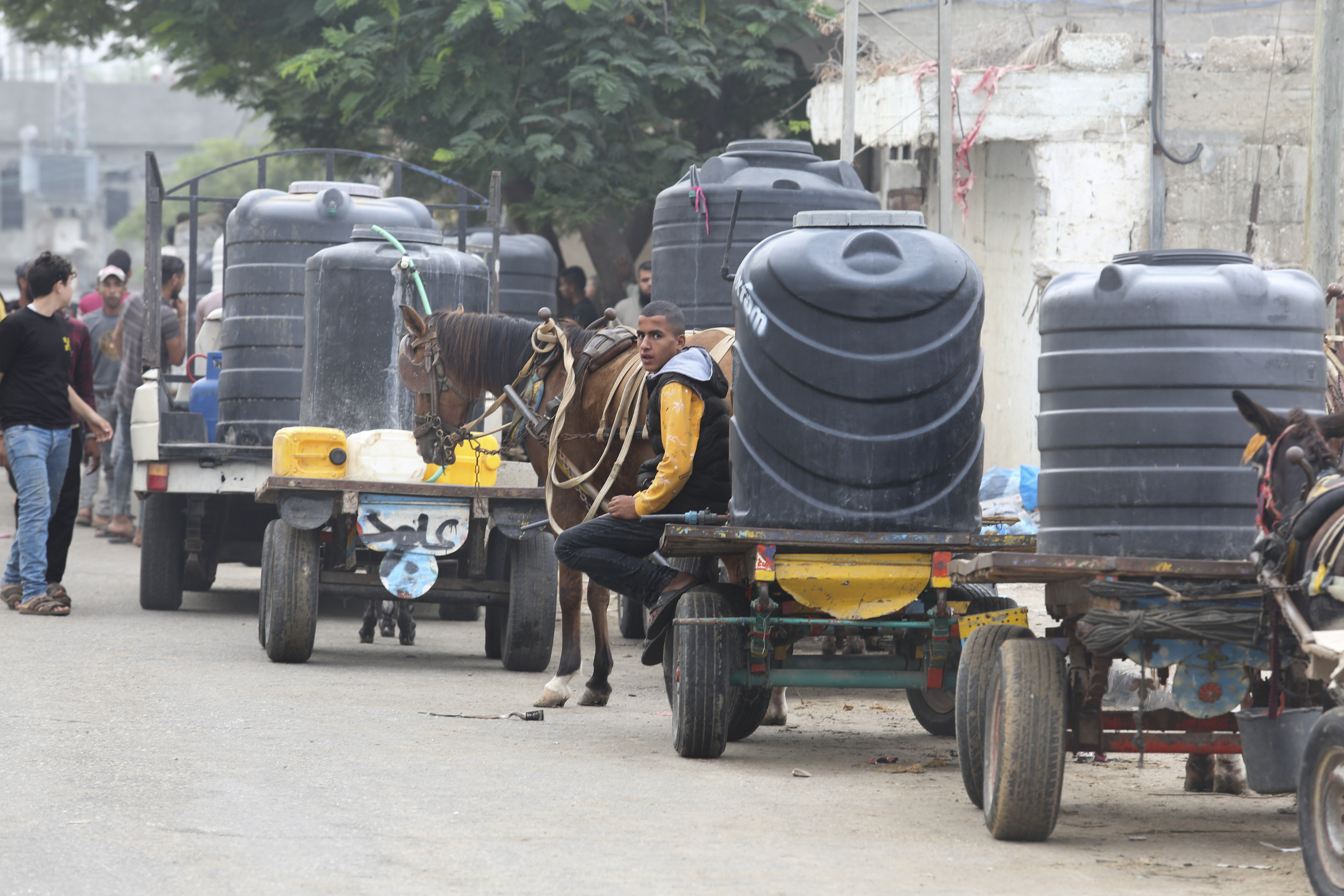 Palestinians wait to collect drinking water during the ongoing Israeli bombardment of the Gaza Strip in Rafah on Saturday