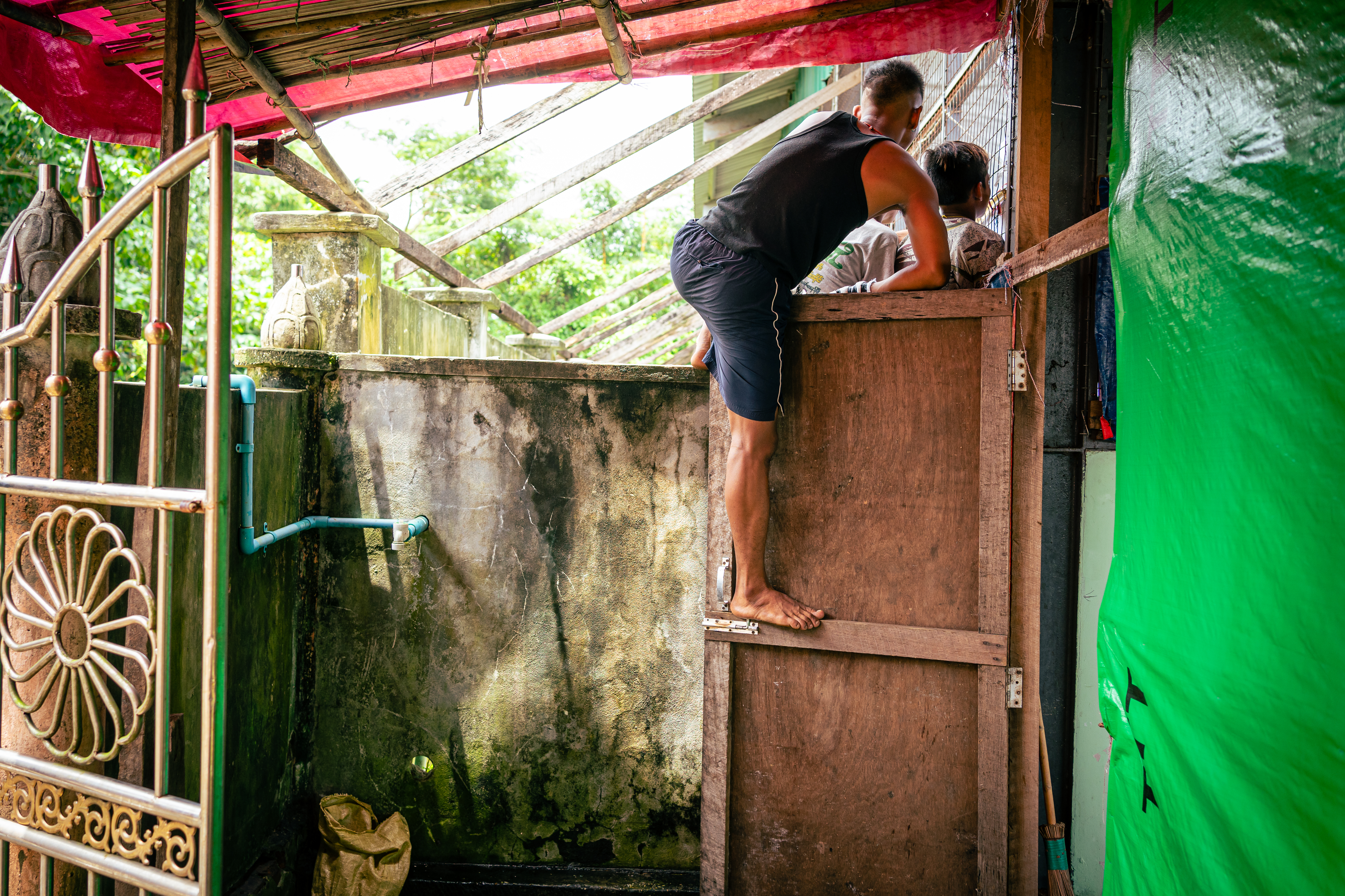 Not everyone is buying a ticket for the bouts – three young people climb atop a wall at the side of the venue in Pantanaw to peek at the flights through an opening.