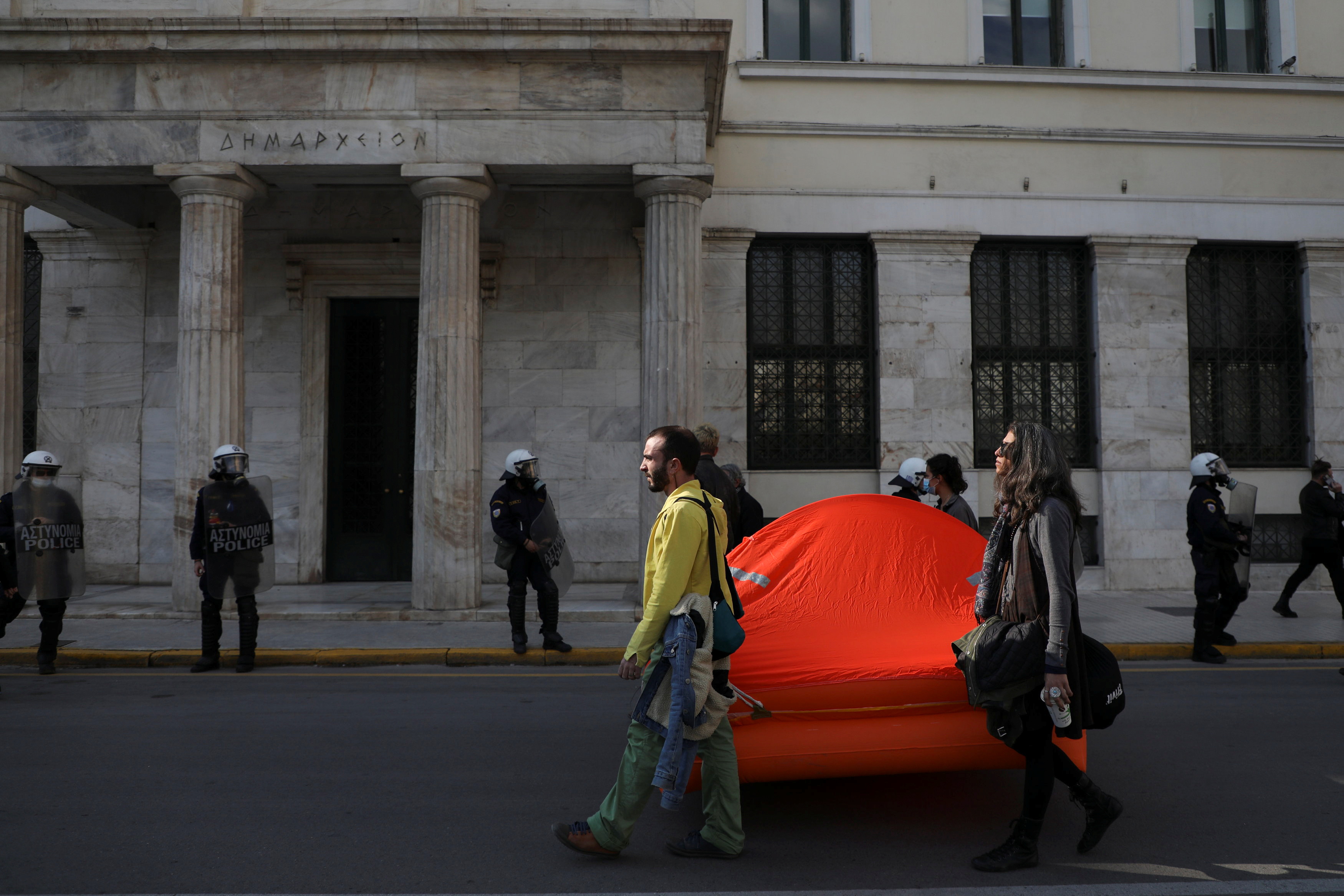 People hold a life raft during a protest against pushbacks and border violence at the Greek-Turkish border after several people were found frozen to death near Turkey's border with Greece in Athens, Greece, February 6, 2022. REUTERS/Louiza Vradi