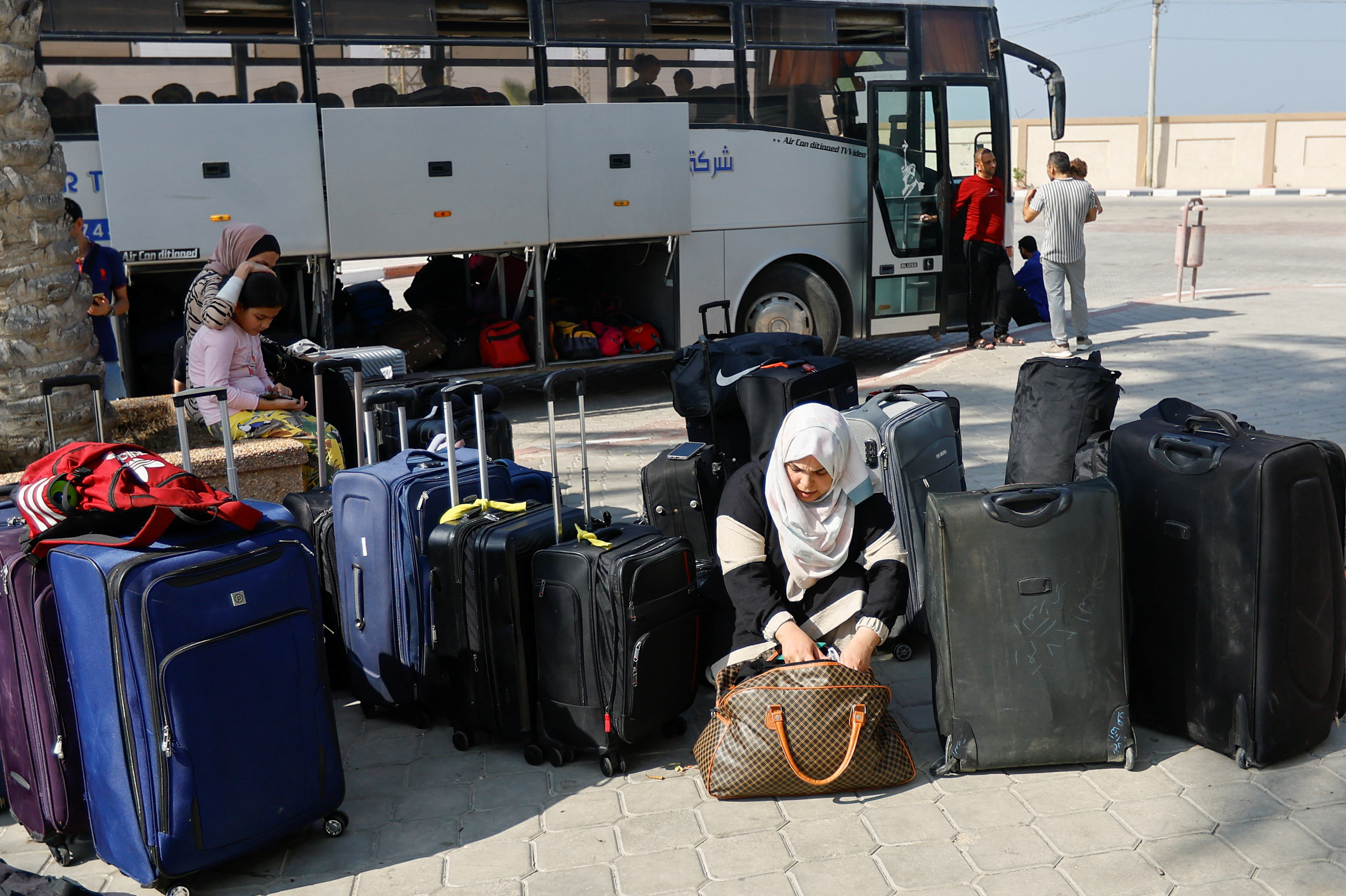 A Palestinian holding a foreign passport looks through her bag as she waits for permission to leave Gaza, amid the ongoing conflict between Israel and Palestinian Islamist group Hamas, at the Rafah border 