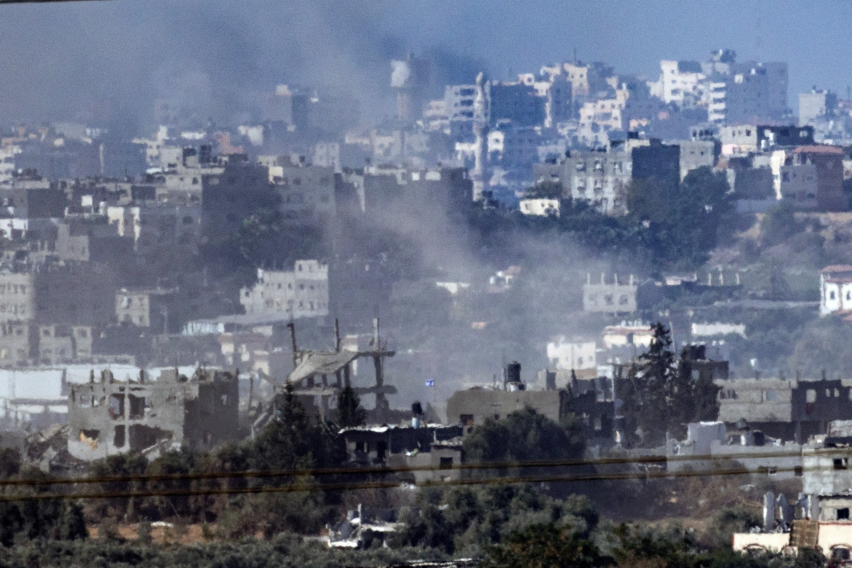 An Israeli flag can be seen inside Gaza Strip, looking in from the Israeli side of the border, on November 11, 2023 [Evelyn Hockstein/Reuters]
