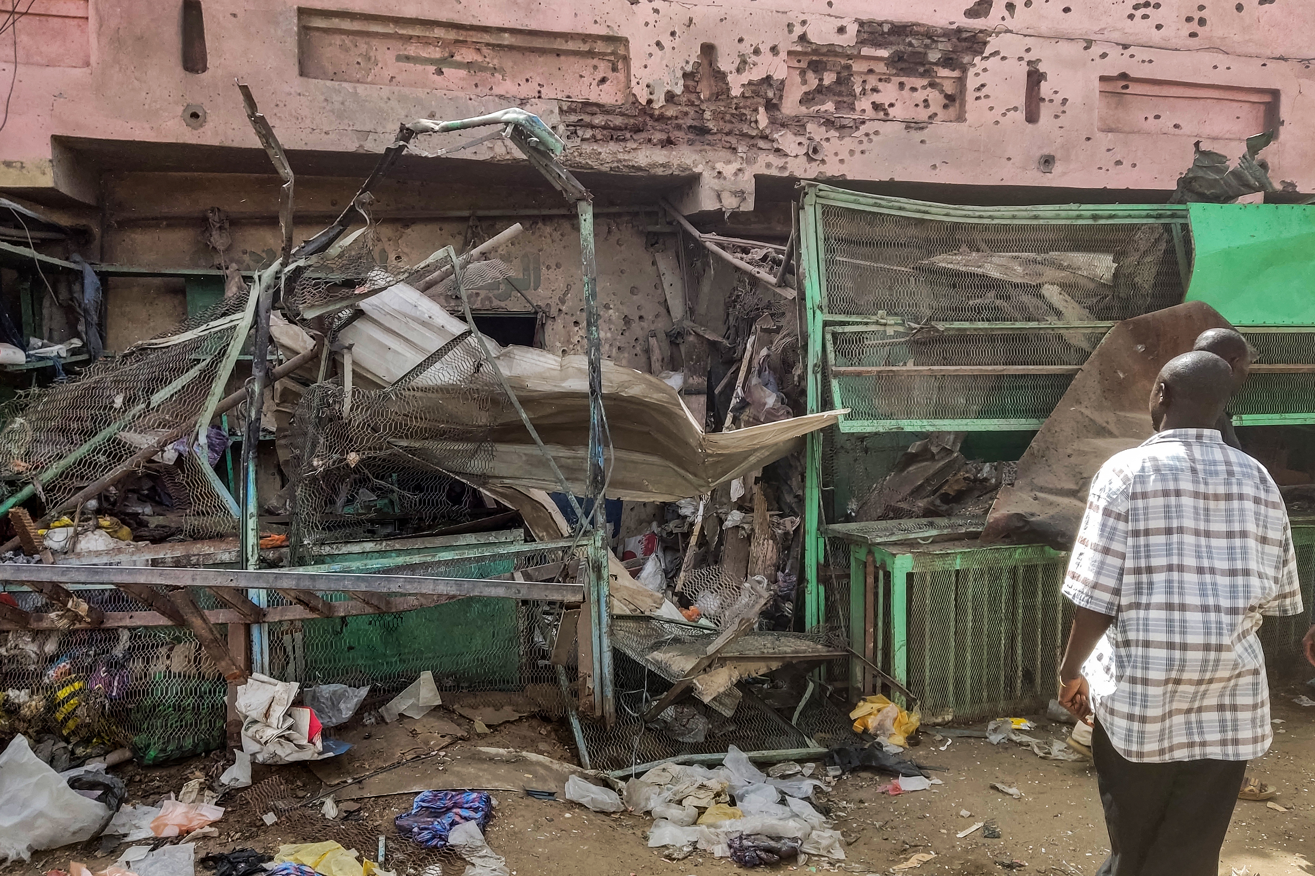 People walk past a medical centre building riddled with bullet holes at the Souk Sitta (Market Six) in the south of Khartoum on June 1, 2023.