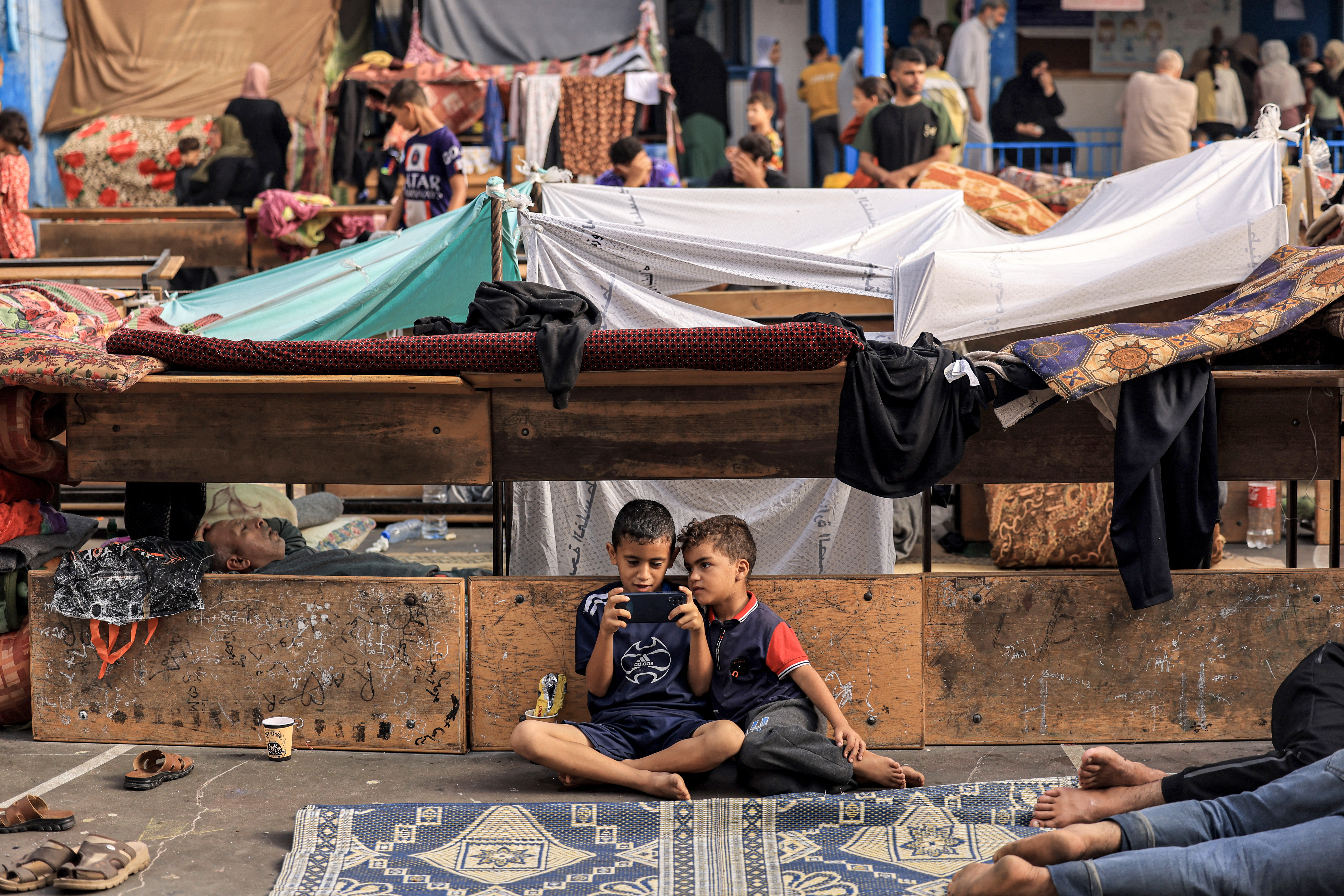 Children sit by a wall in Gaza