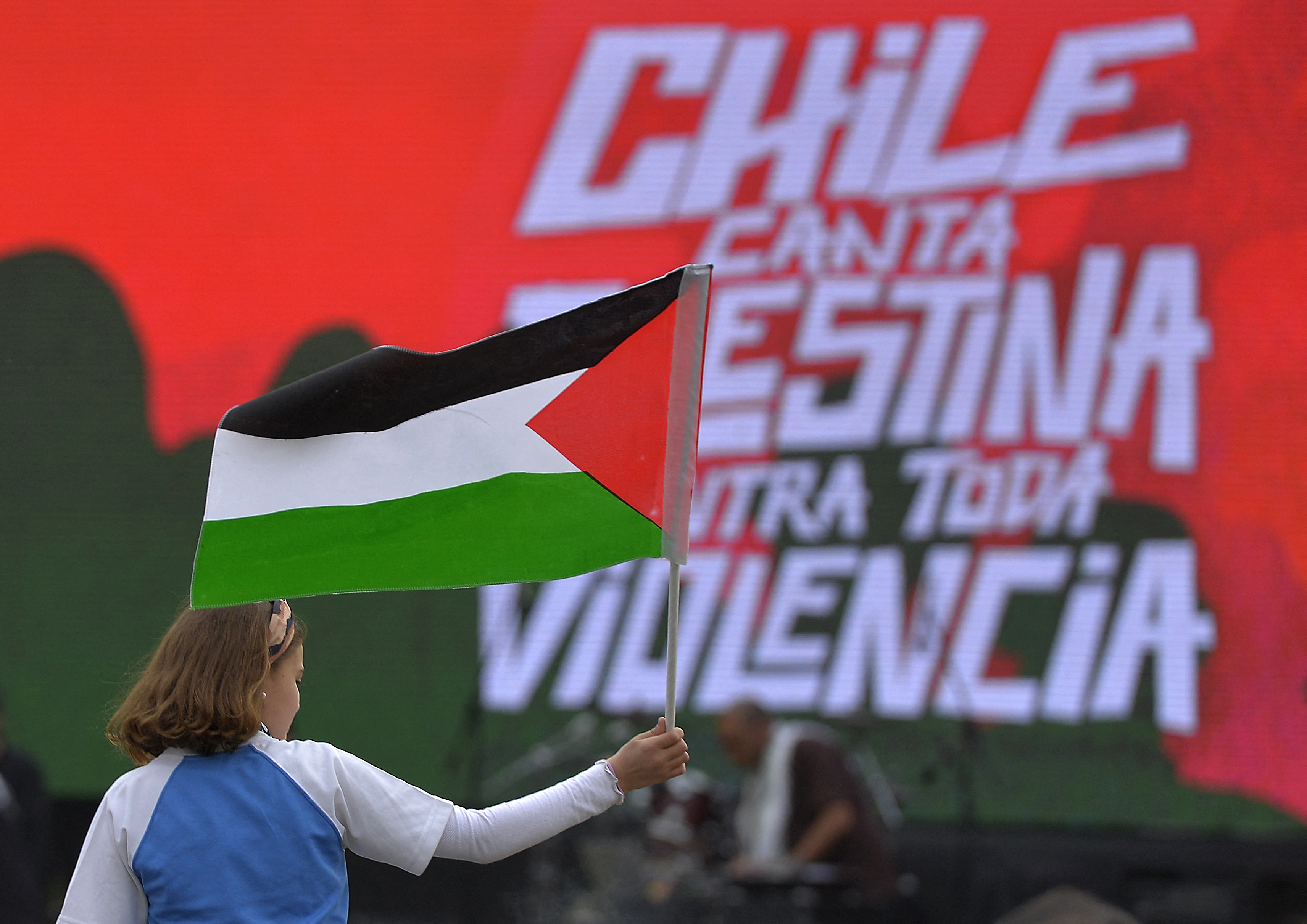 A girl waves a Palestinian flag during "Chile Sings Palestine Against all Violence", a festival with more than 20 national and international artists organized by the Palestinian community of Chile, which aims to support the victims in Gaza, at Padre Hurtado Park in Santiago, on October 25, 2023. - Thousands of civilians, both Palestinians and Israelis, have died since October 7, 2023, after Palestinian Hamas militants based in the Gaza Strip entered southern Israel in an unprecedented attack triggering a war declared by Israel on Hamas with retaliatory bombings on Gaza. (Photo by Guillermo SALGADO / AFP)