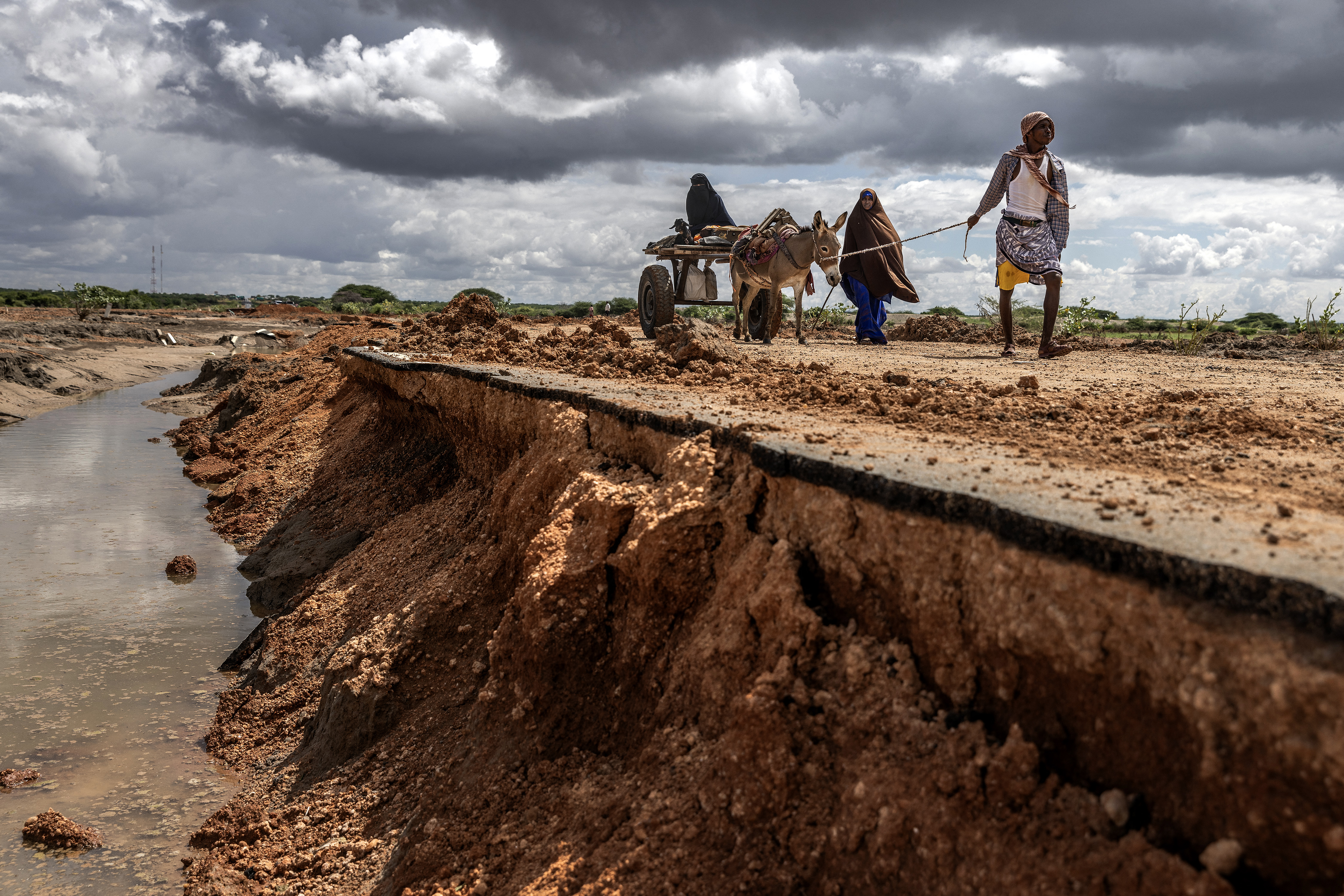 A family carrying their belongings on a cart pulled by a donkey walk towards a village on a road destroyed by flash floods at the Garissa-Wajir Road in Maalimin.
