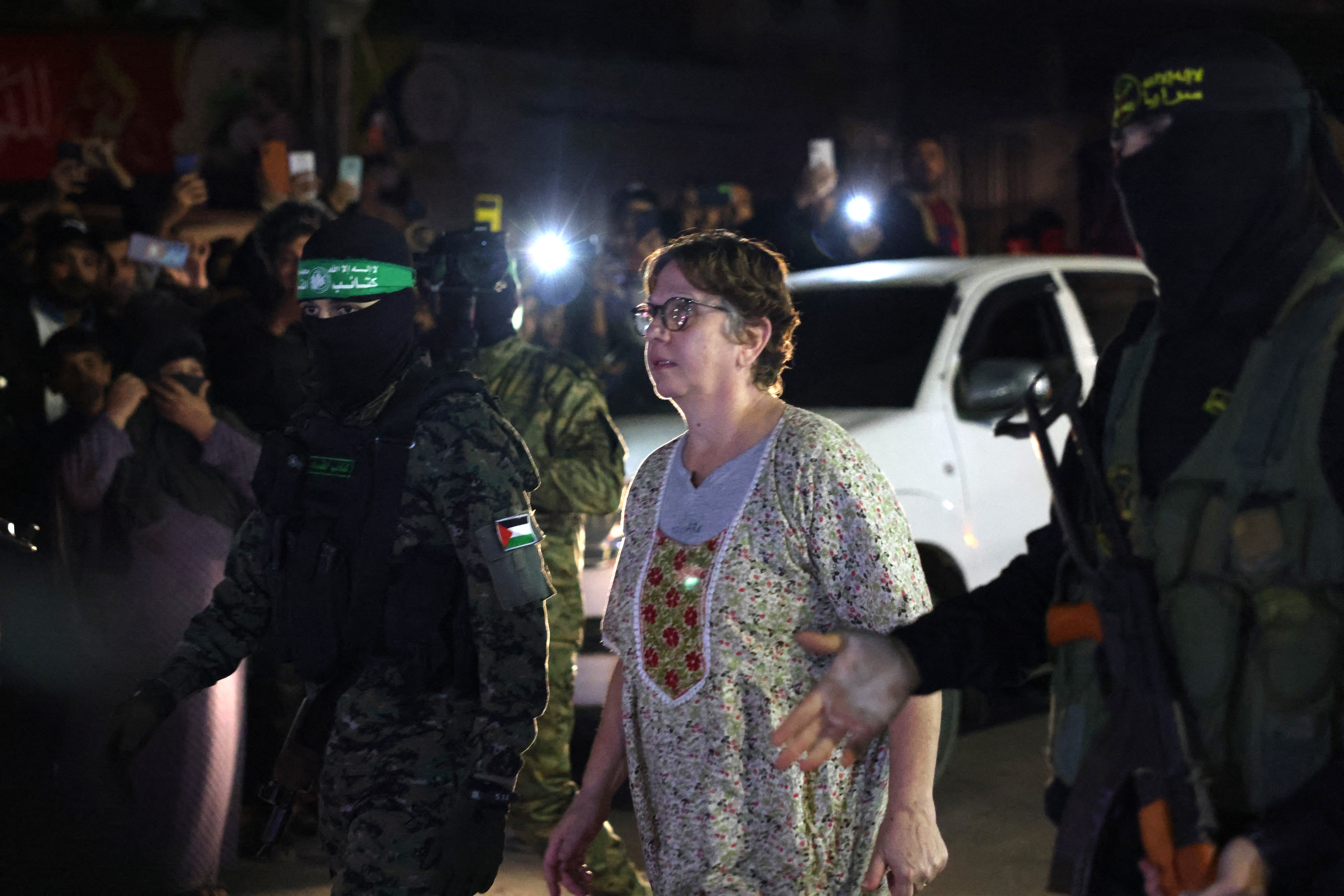Hamas and Islamic Jihad fighters accompany a newly released hostage before handing them over to the Red Cross in Rafah, in the southern Gaza Strip on November 28