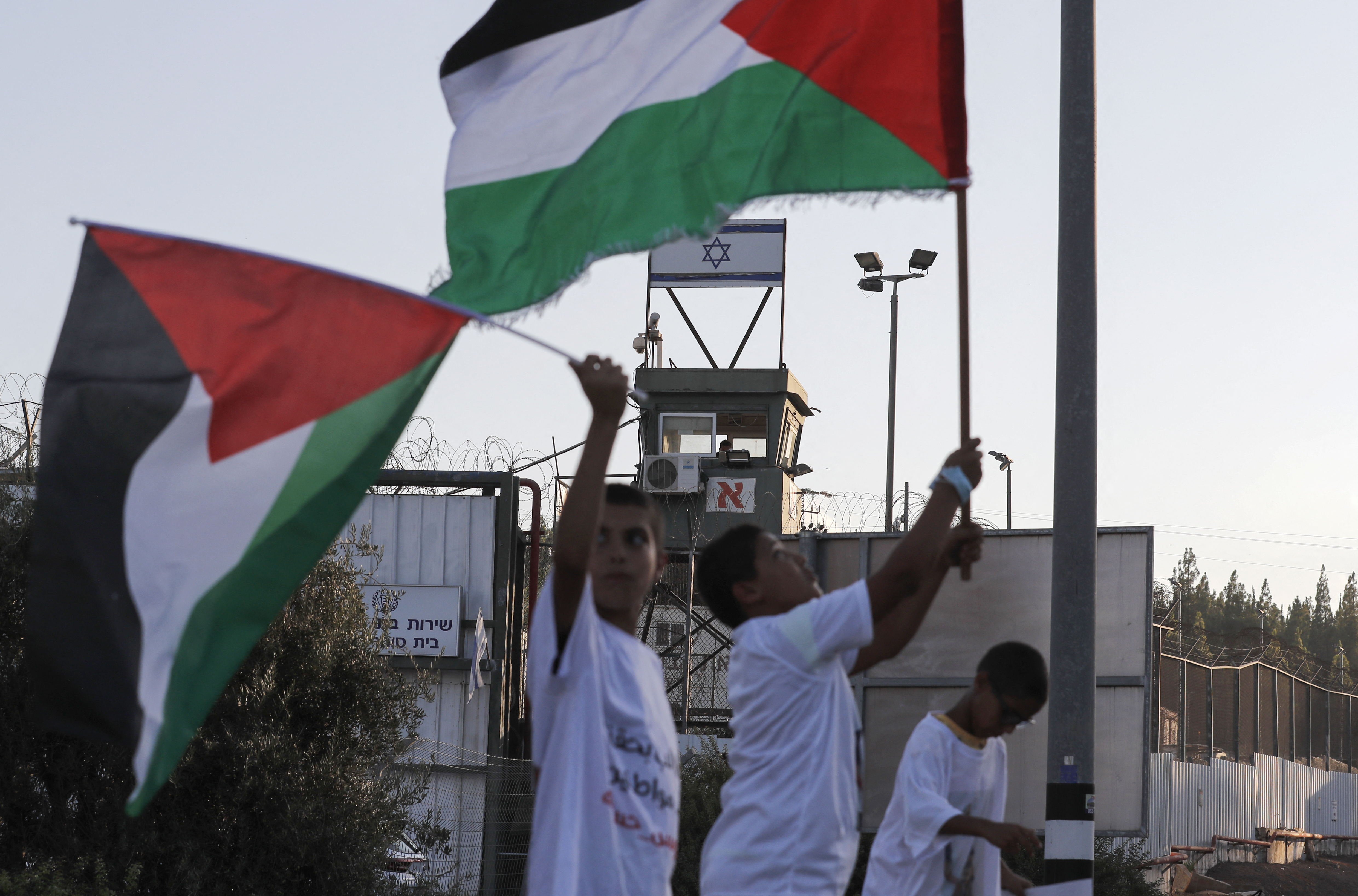 Arab Israelis lift Palestinian flags and placards during a protest outside the Megiddo prison in northern Israel on August 22, 2021, to demand the release of prisoners from their community jailed following clashes with Jewish Israelis in May in Lod and other cities. (Photo by Ahmad GHARABLI / AFP)