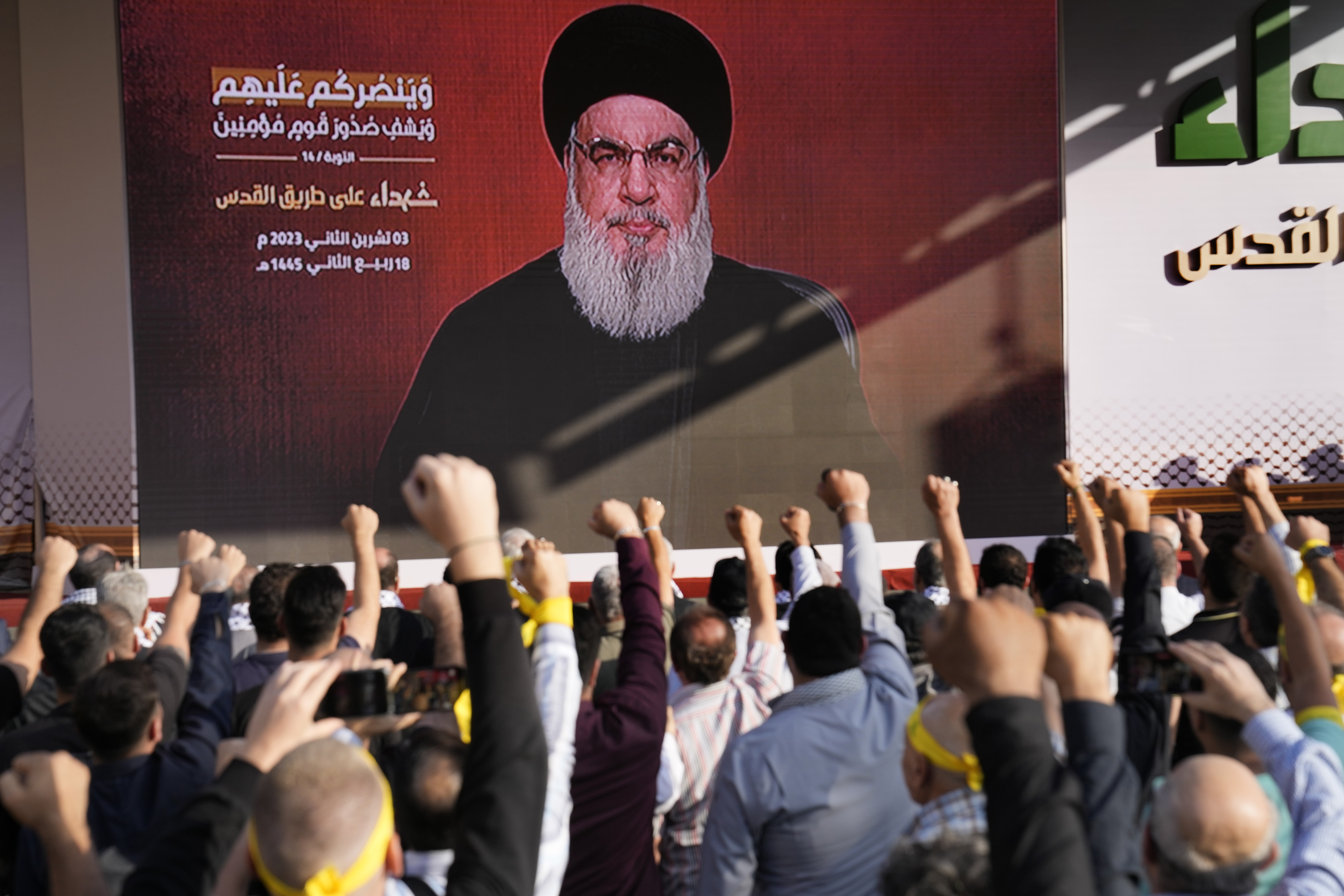 Supporters of the Iranian-backed Hezbollah group raise their fists and cheer as Hezbollah leader Sayyed Hassan Nasrallah appears via a video link, during a rally to commemorate Hezbollah fighters who were killed in South Lebanon last few weeks while fighting against the Israeli forces, in Beirut, Lebanon.