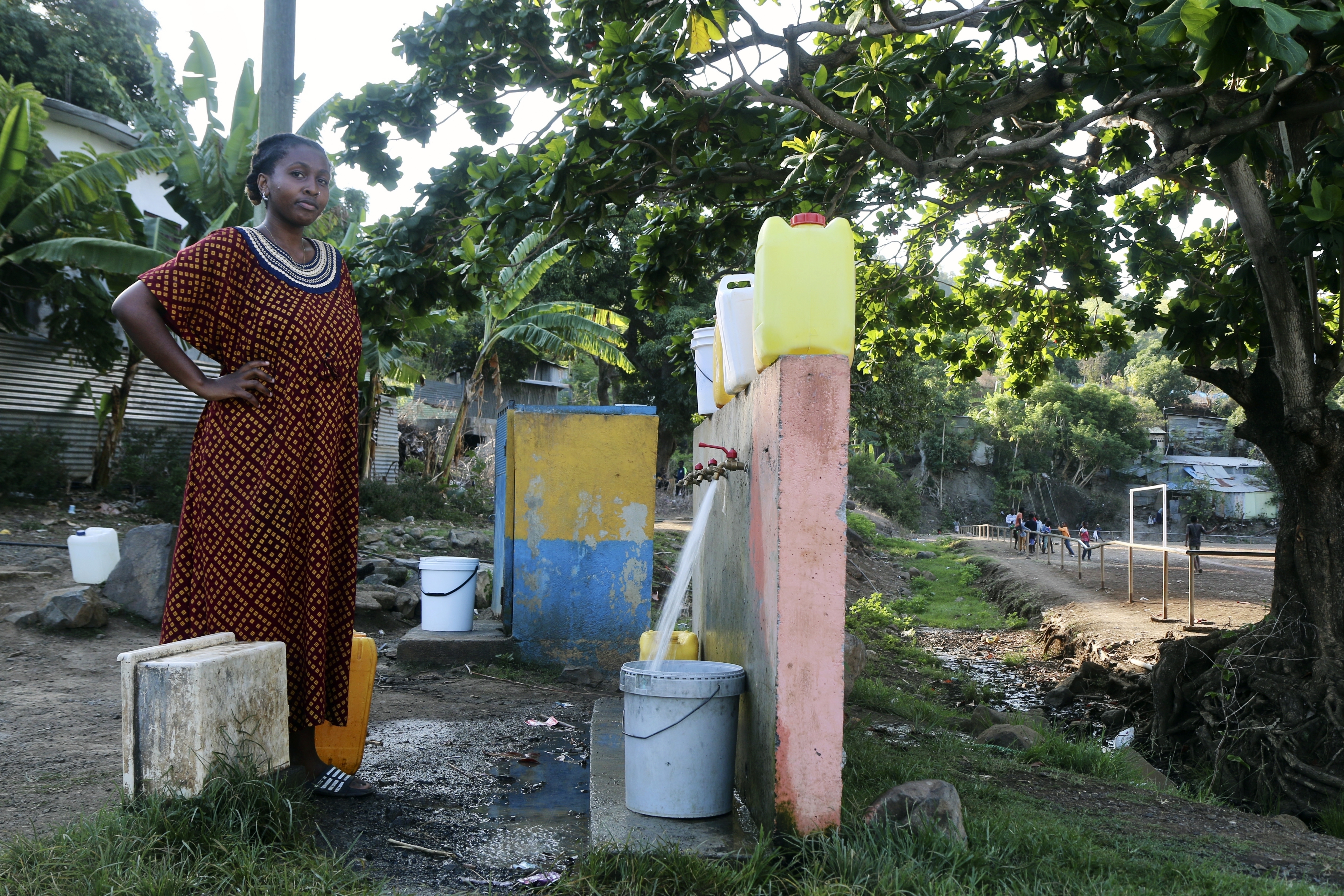 A woman waits for her bucket to be full at a water point in M'tsamoudou, near Bandrele, on the French Indian Ocean territory of Mayotte.