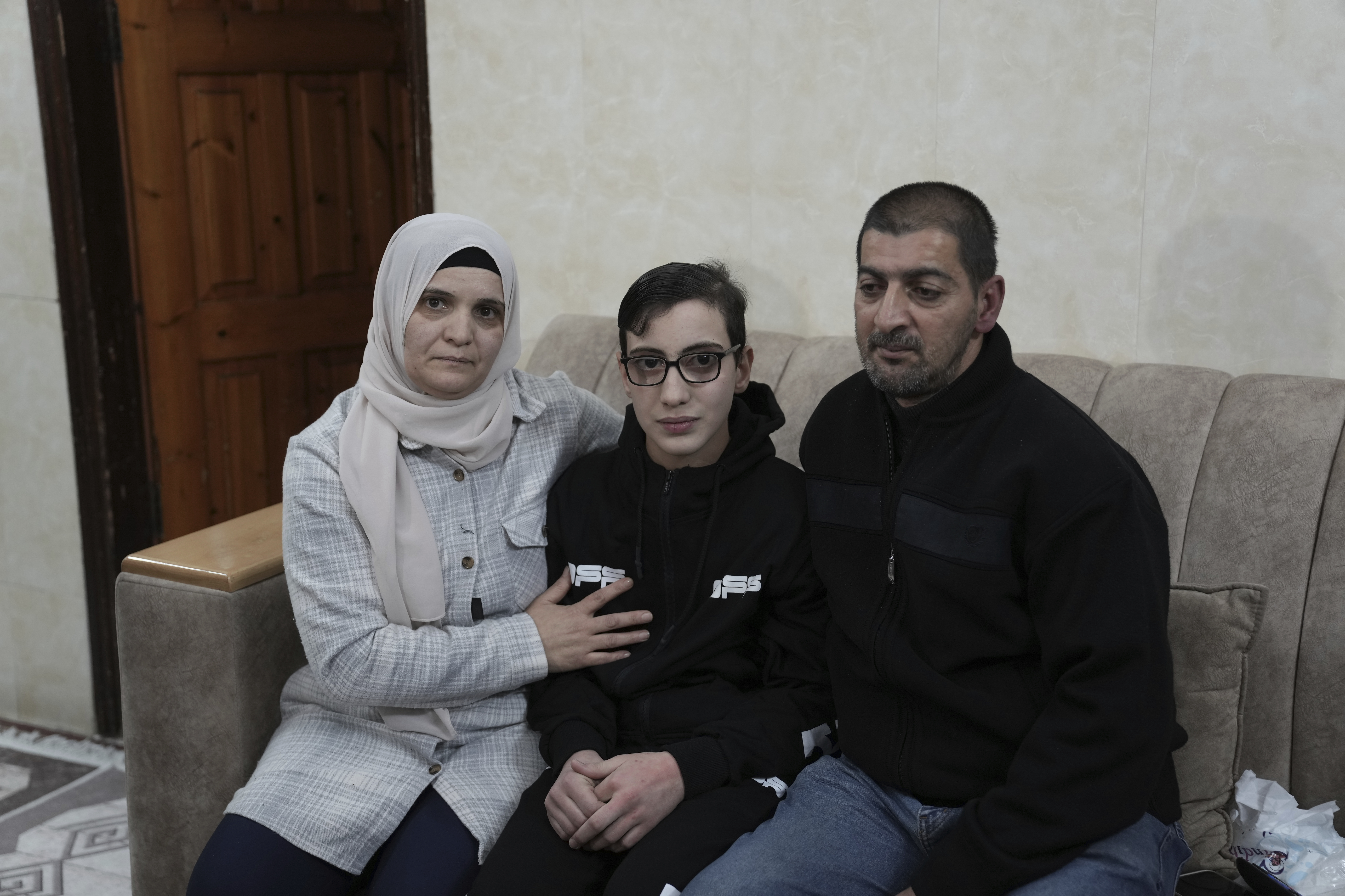 Moataz Salaima, 15, center, a Palestinian prisoner released by Israel, poses for a photo with his parents as he arrives home in the east Jerusalem neighborhood of Ras al-Amud.
