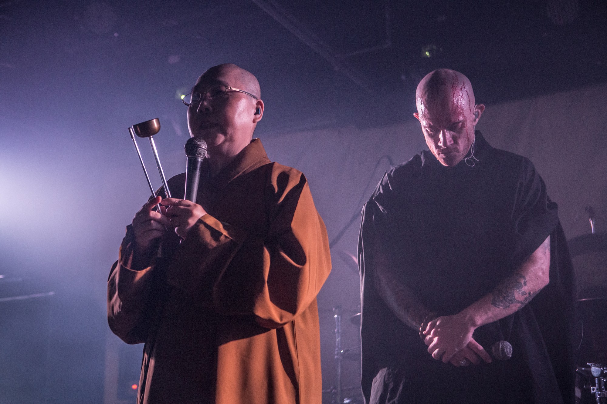 Master Miao-ben on stage in their roves. Lead singer Jon Henley is behind with his head bowed 