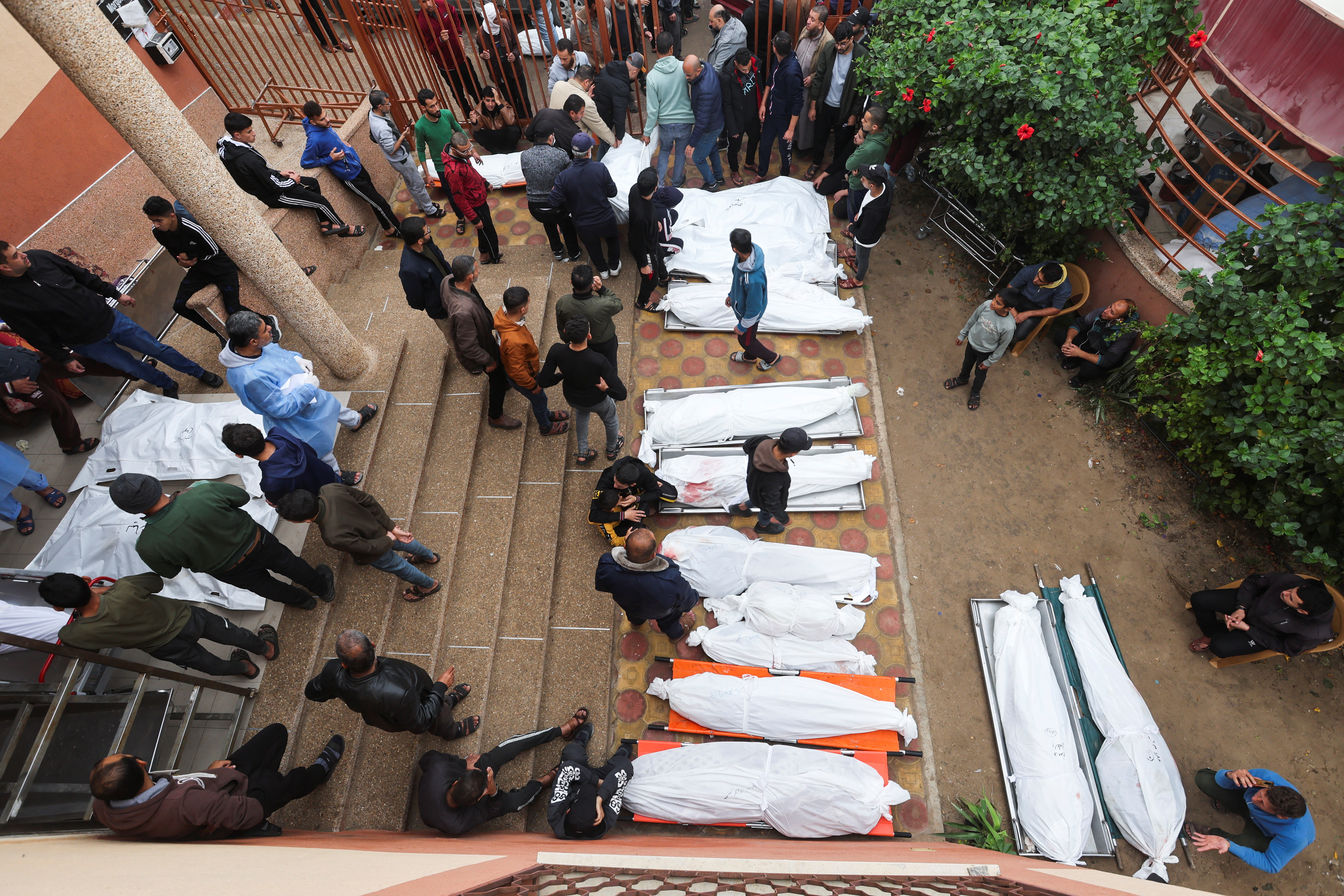 People stand near bodies of Palestinians who were killed during Israeli strikes on Ma'an school east of Khan Younis
