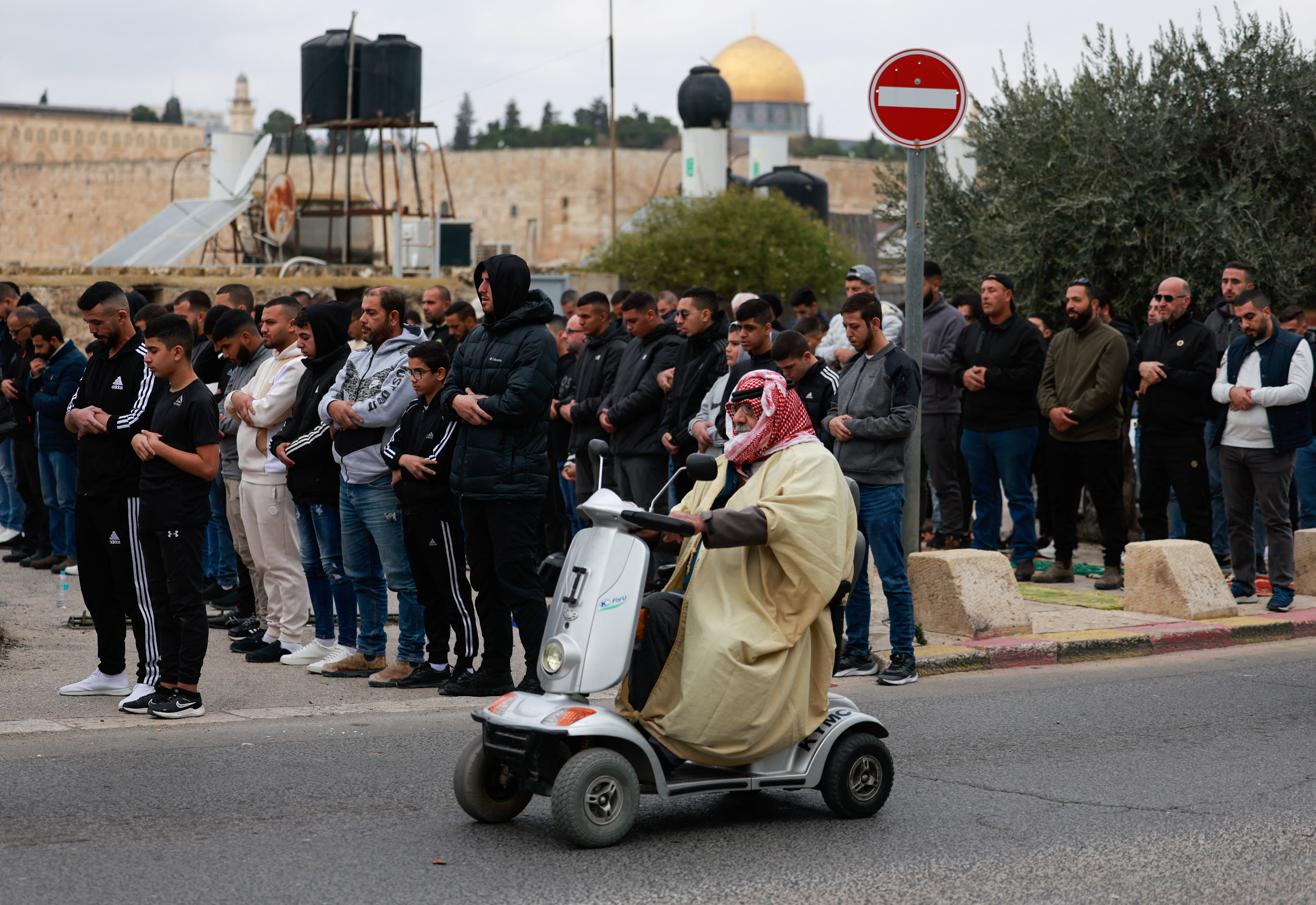 A man sits on a mobility scooter, while Palestinian Muslims hold Friday prayers, as the conflict between Israel and the Palestinian Islamist group Hamas continues, in Jerusalem, December 29