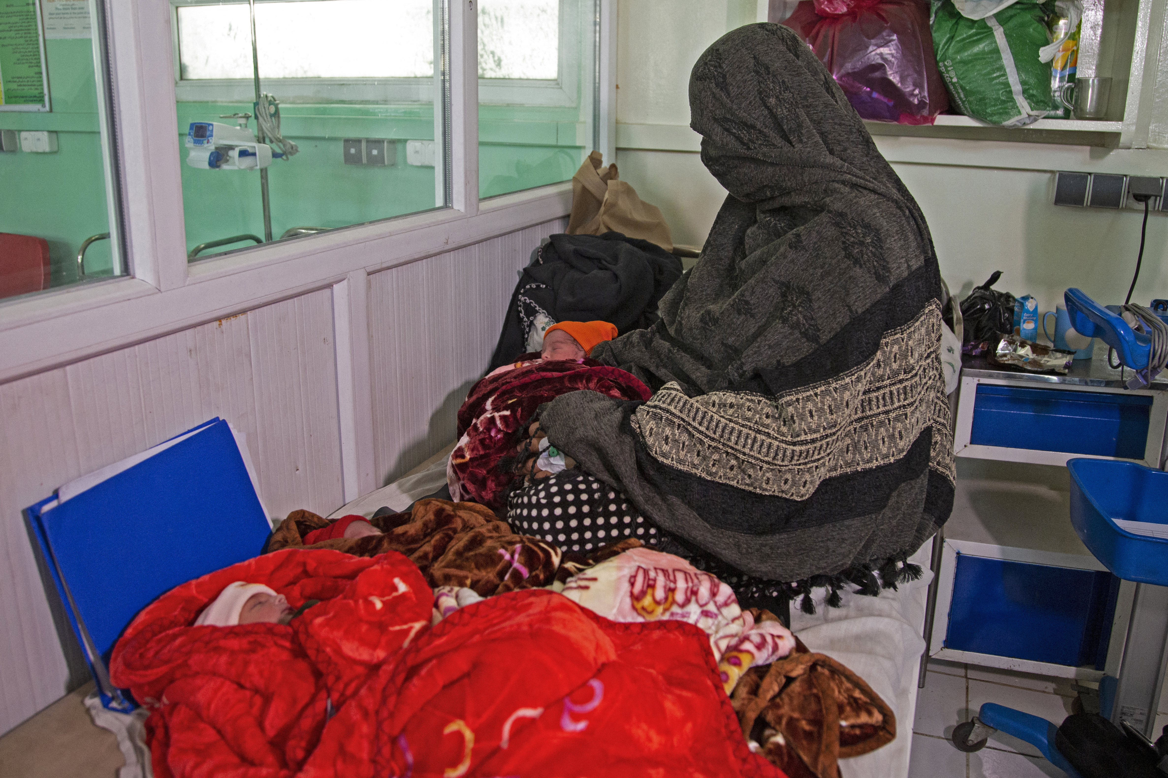 In this photograph taken on December 8, 2023, Islam Bibi, mother of six children and newborn triplets, sits beside her three babies at the Doctors Without Borders (MSF)-run maternity hospital in Khost.