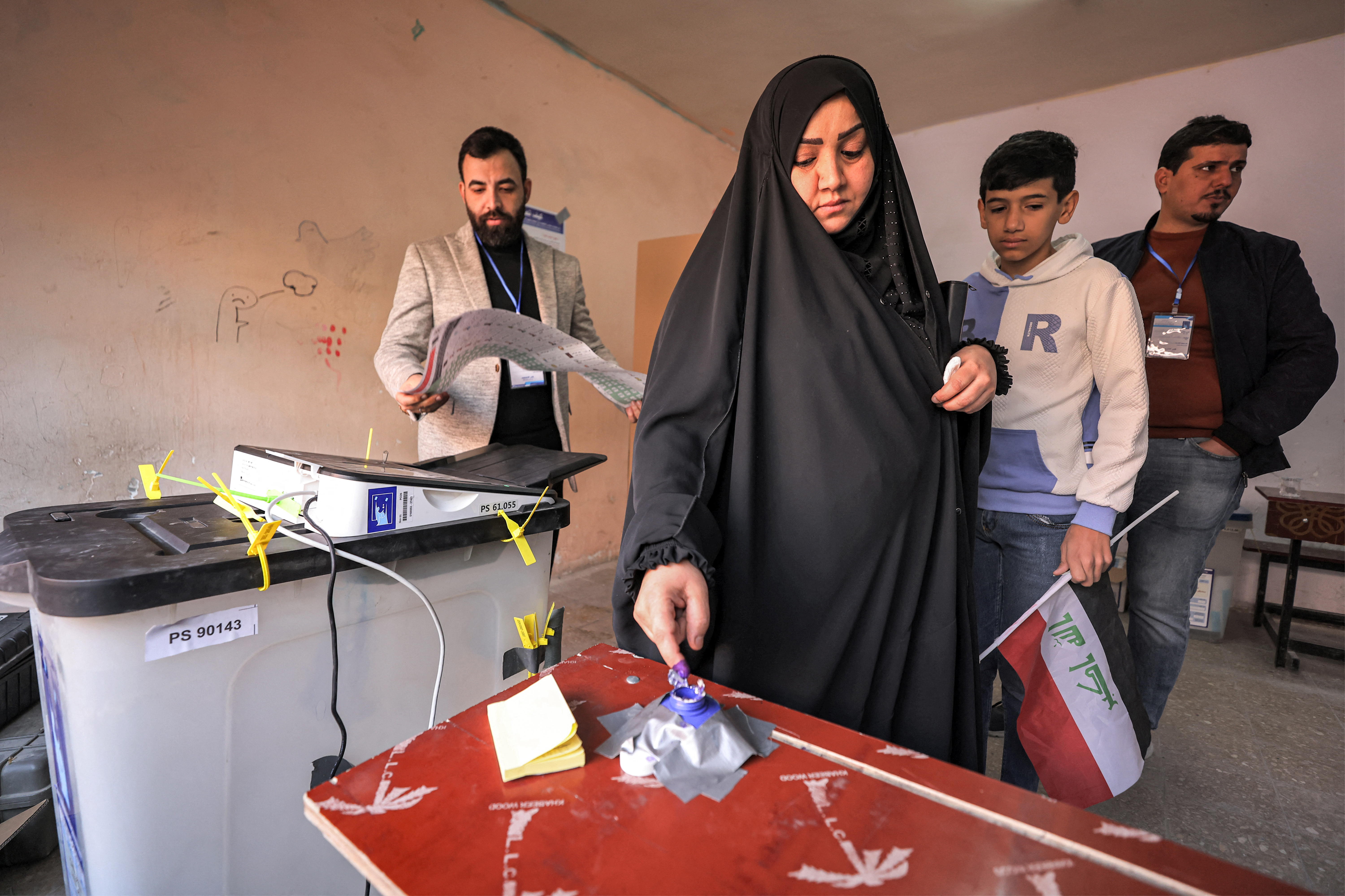 A woman dips her finger in ink after voting in the 2023 Iraqi provincial council elections, the first such vote in a decade, at a polling station in Sadr City in eastern Baghdad, on December 18, 2023. (Photo by AHMAD AL-RUBAYE / AFP)