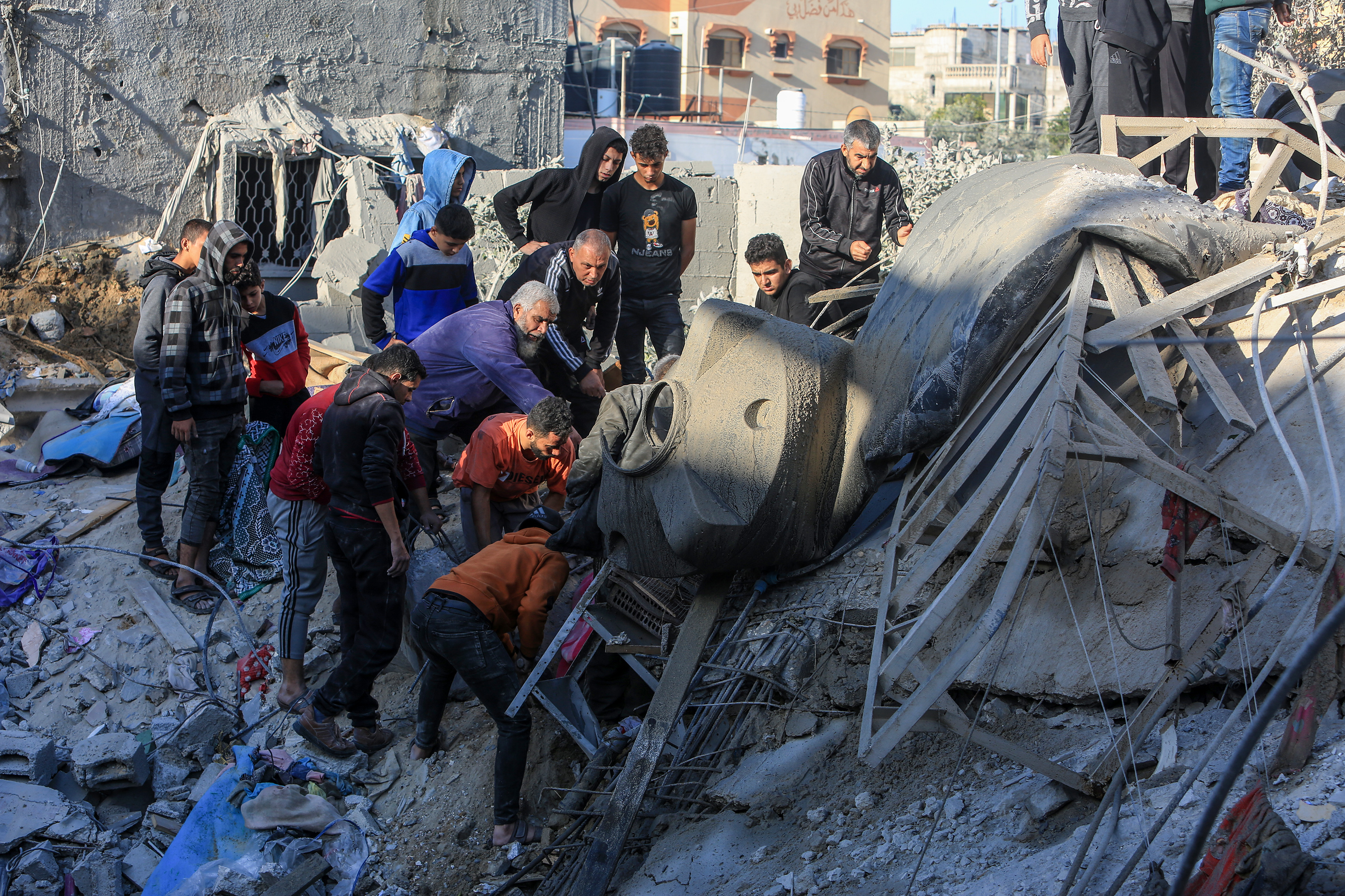 RAFAH, GAZA - DECEMBER 03: Residents conduct a search and rescue operation among the destroyed buildings after Israeli attacks hit the apartment belonging to the Azuum family in Rafah