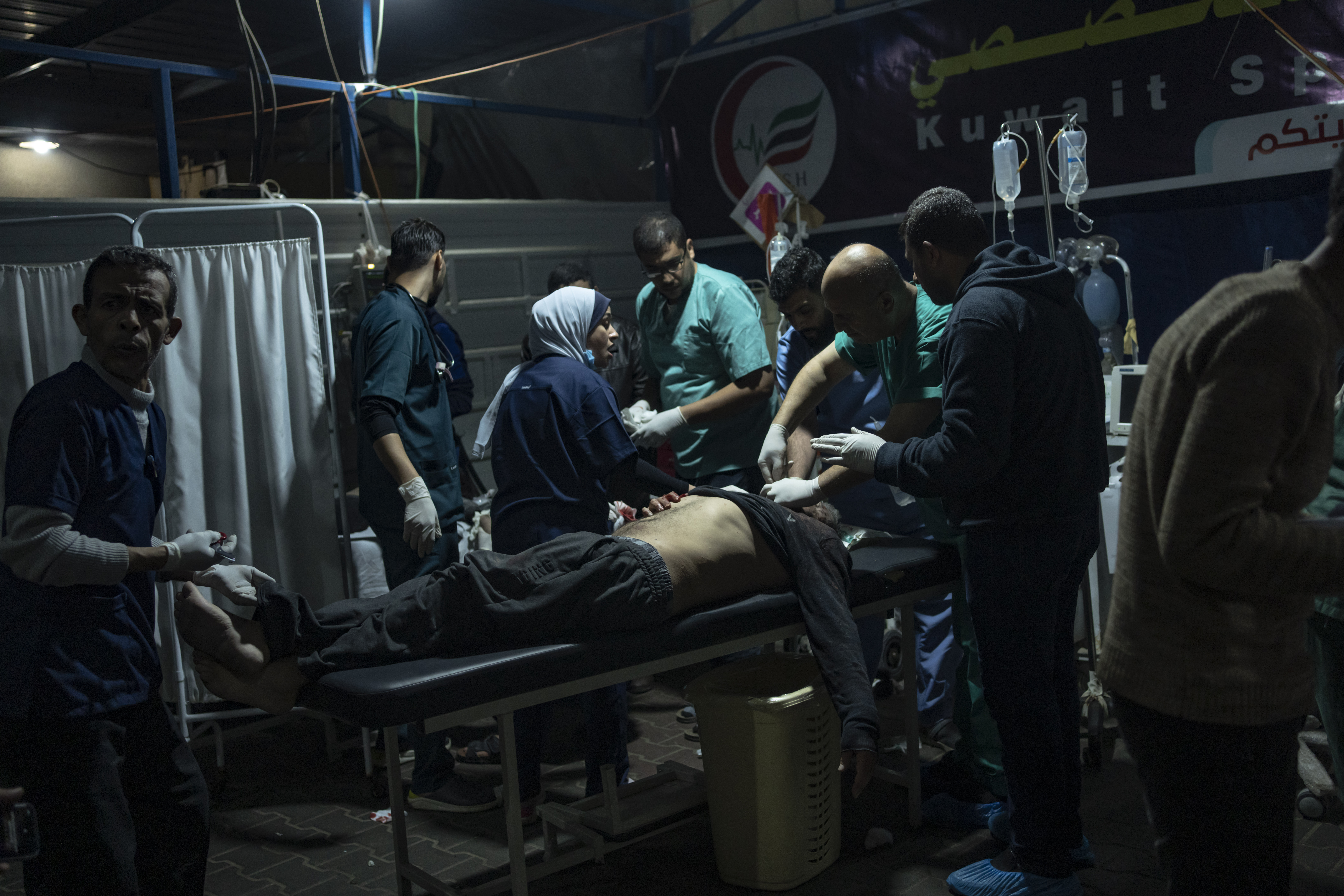 Doctors in dim light treating wounded Palestinian