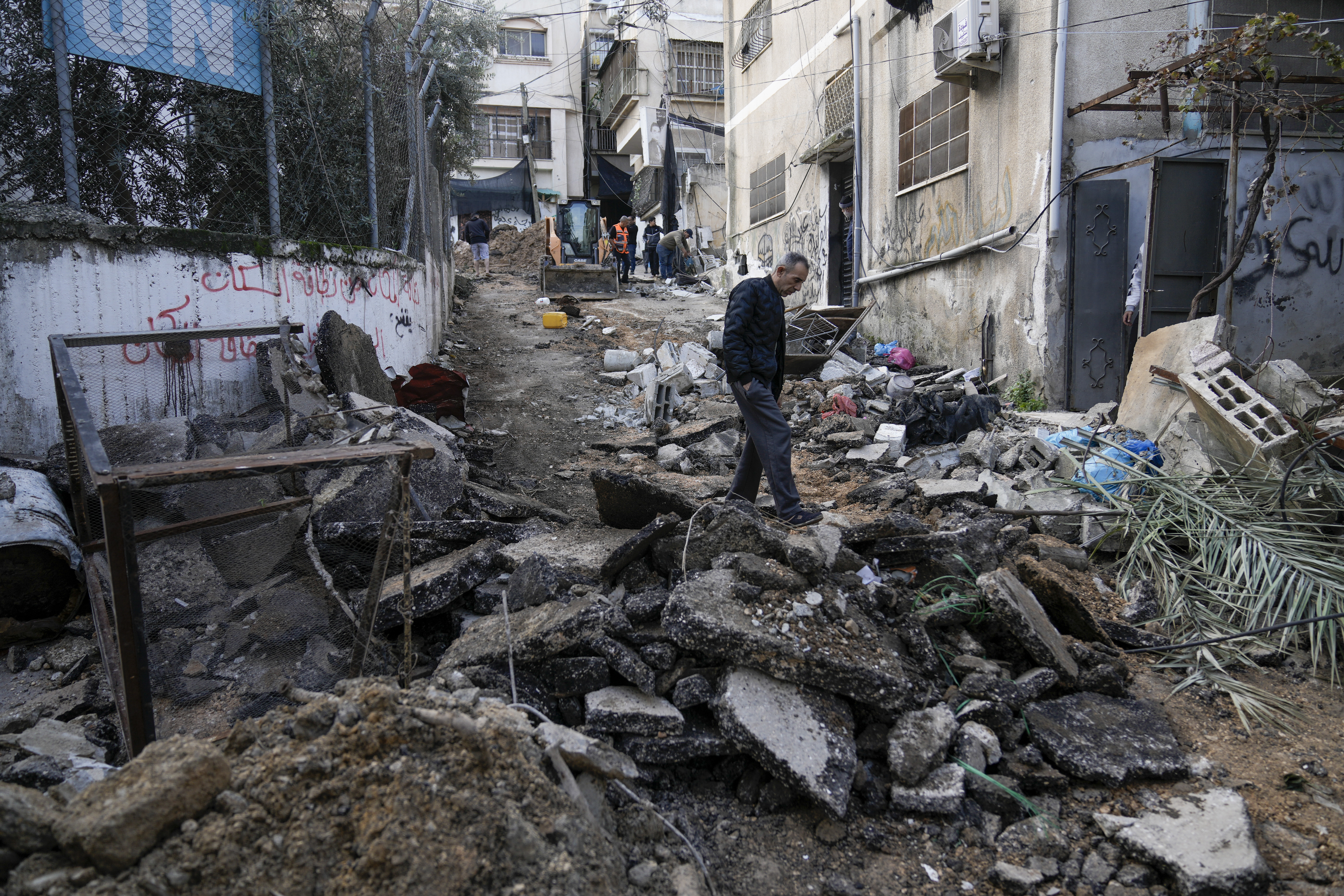 Palestinians walk through the aftermath of the Israeli military raid on Nur Shams refugee camp in the West Bank