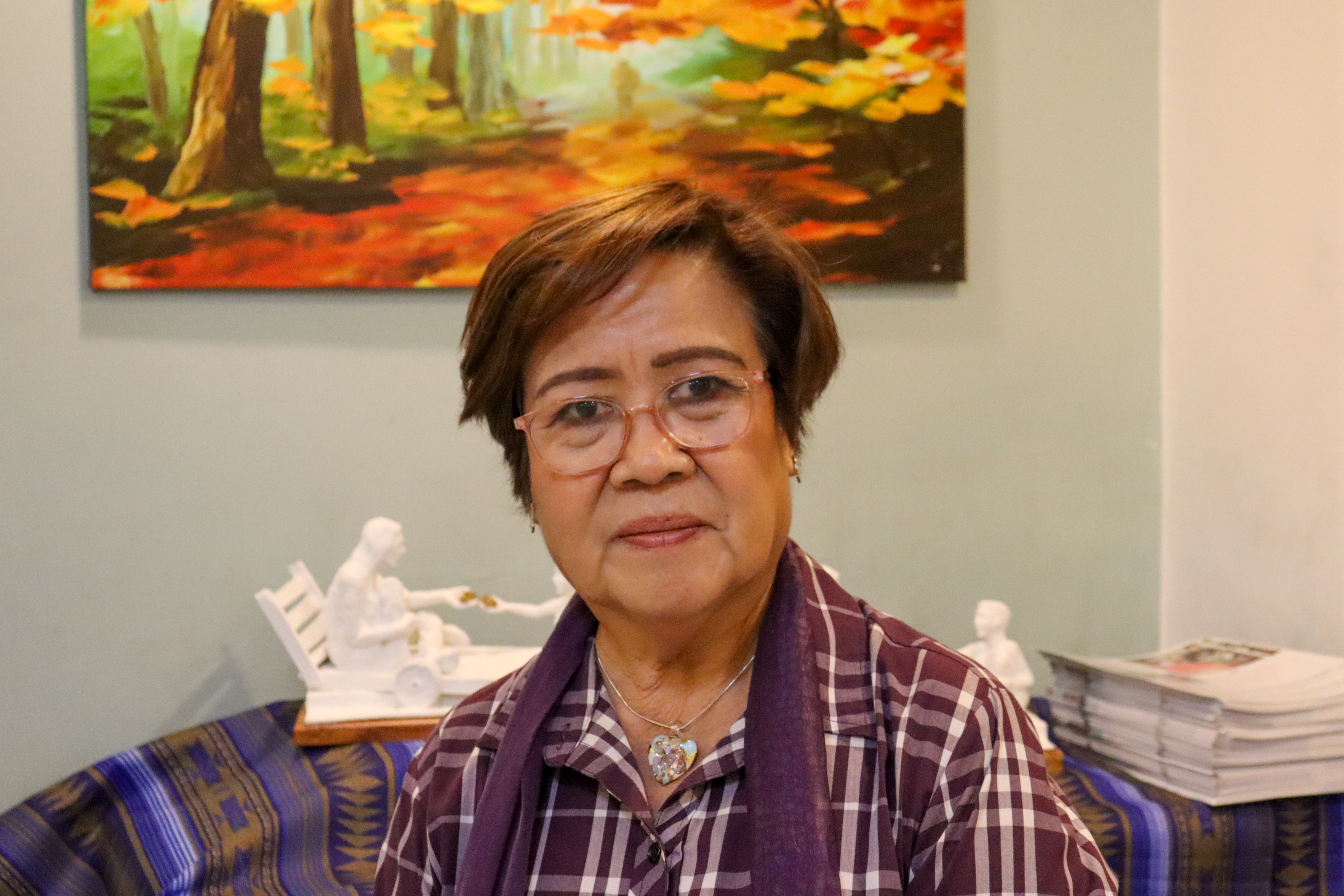 Former Philippine senator Leila de Lima. She is sitting in her office. There is a painting on the wall behind her.