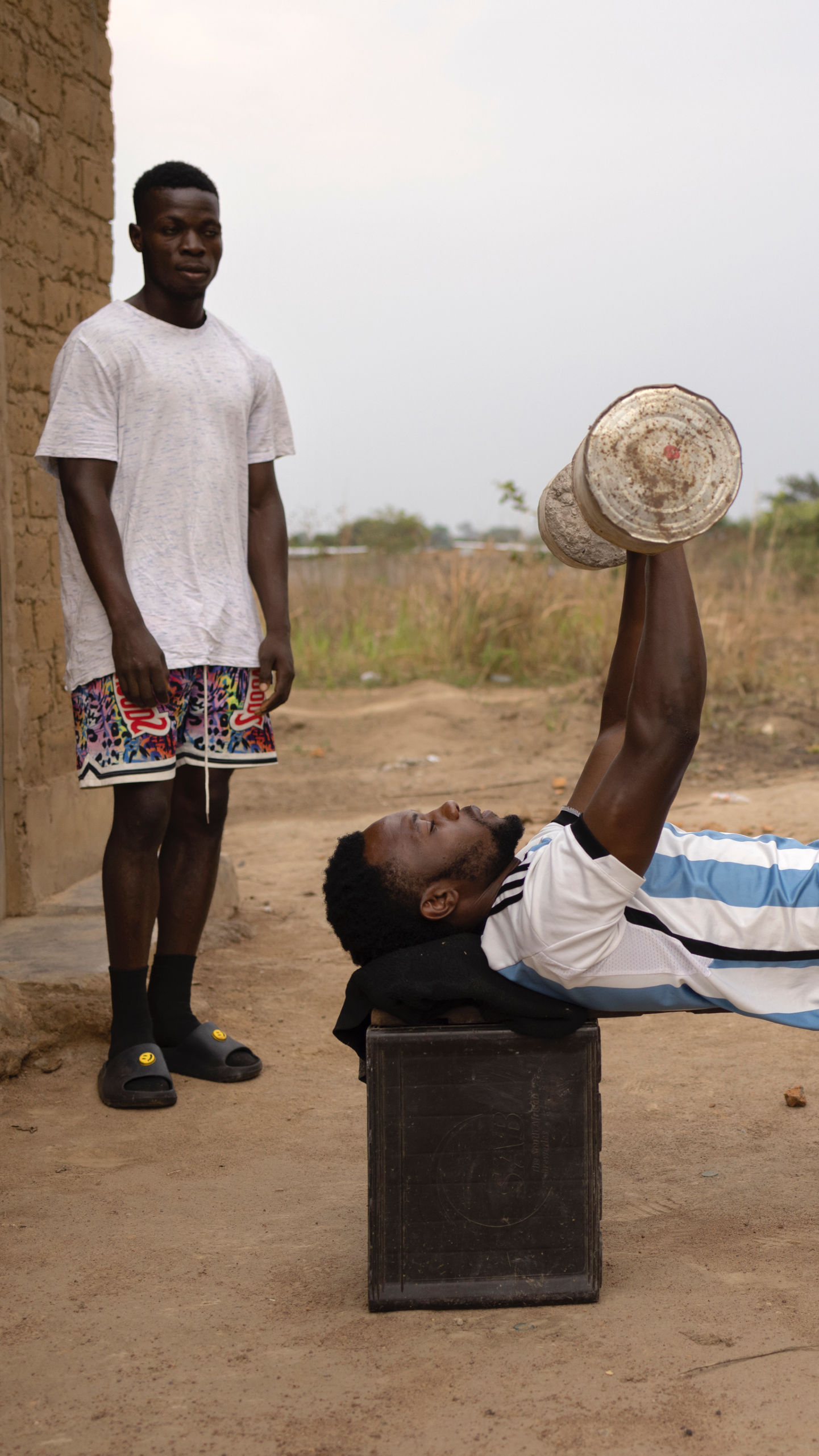Two young men train using makeshift weights