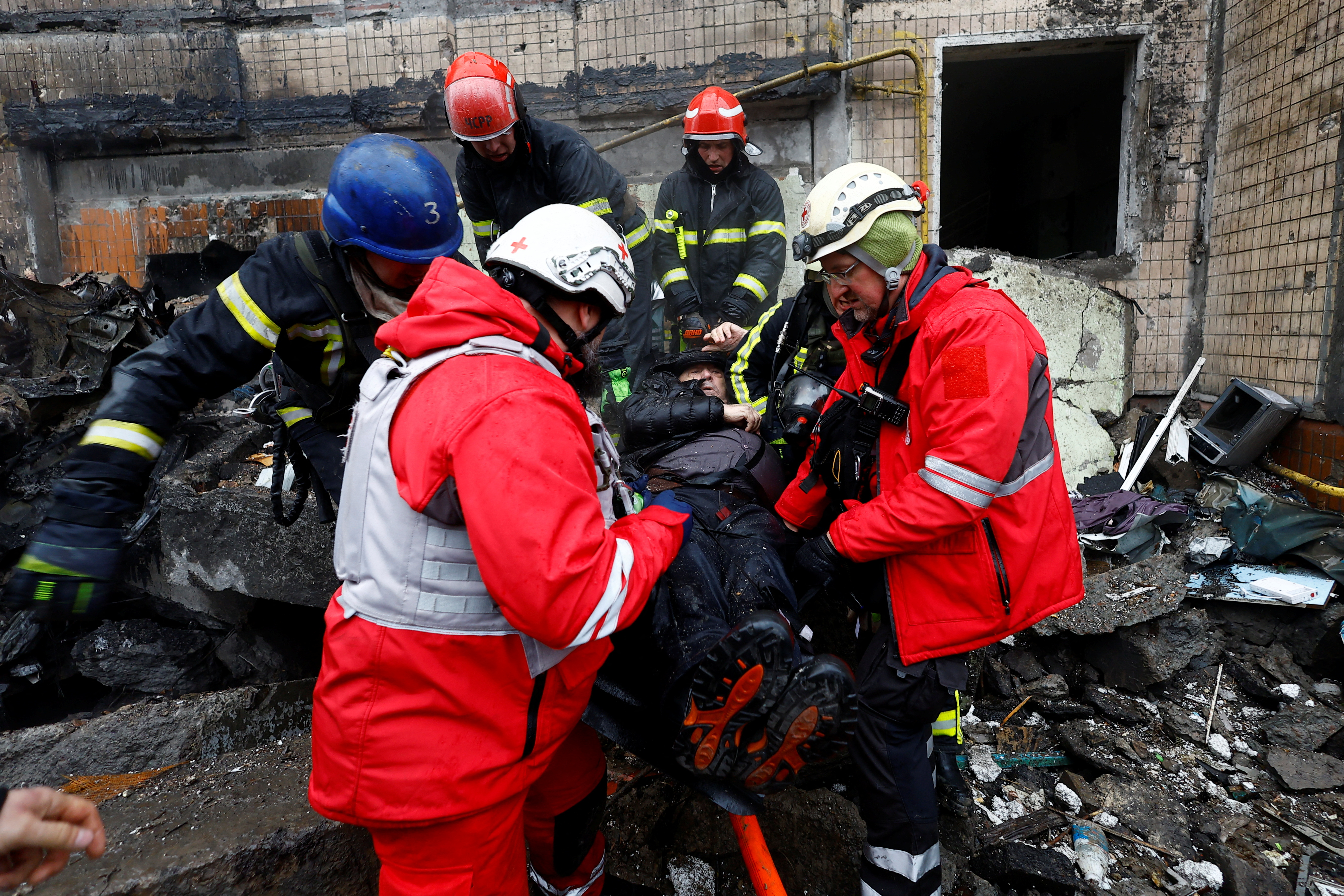 Firefighters rescue a local resident from a site of a residential building heavily damaged during a Russian missile attack, amid Russia's attack on Ukraine, in Kyiv