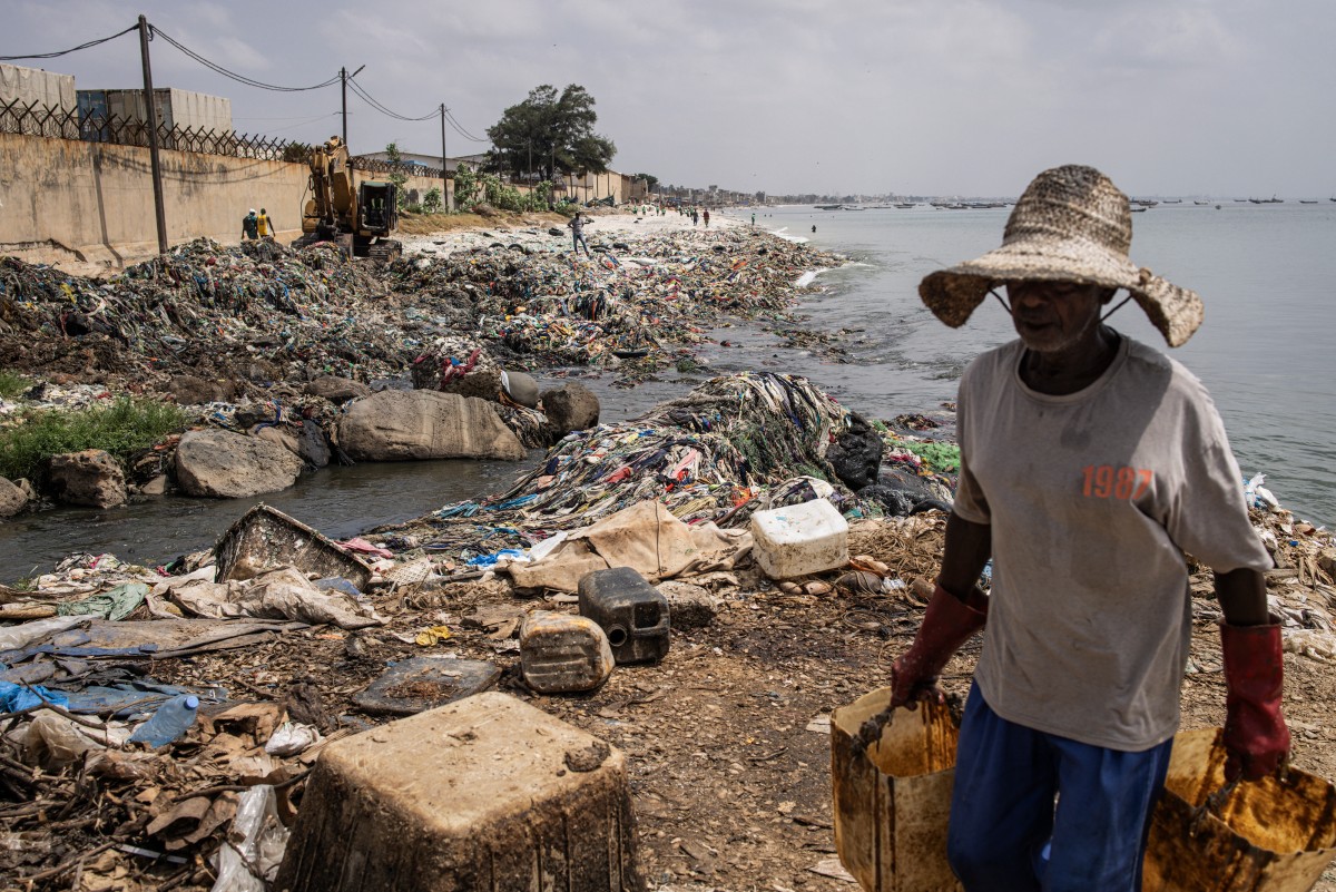 A man carries buckets after dumping waste into a canal along Hann Bay 