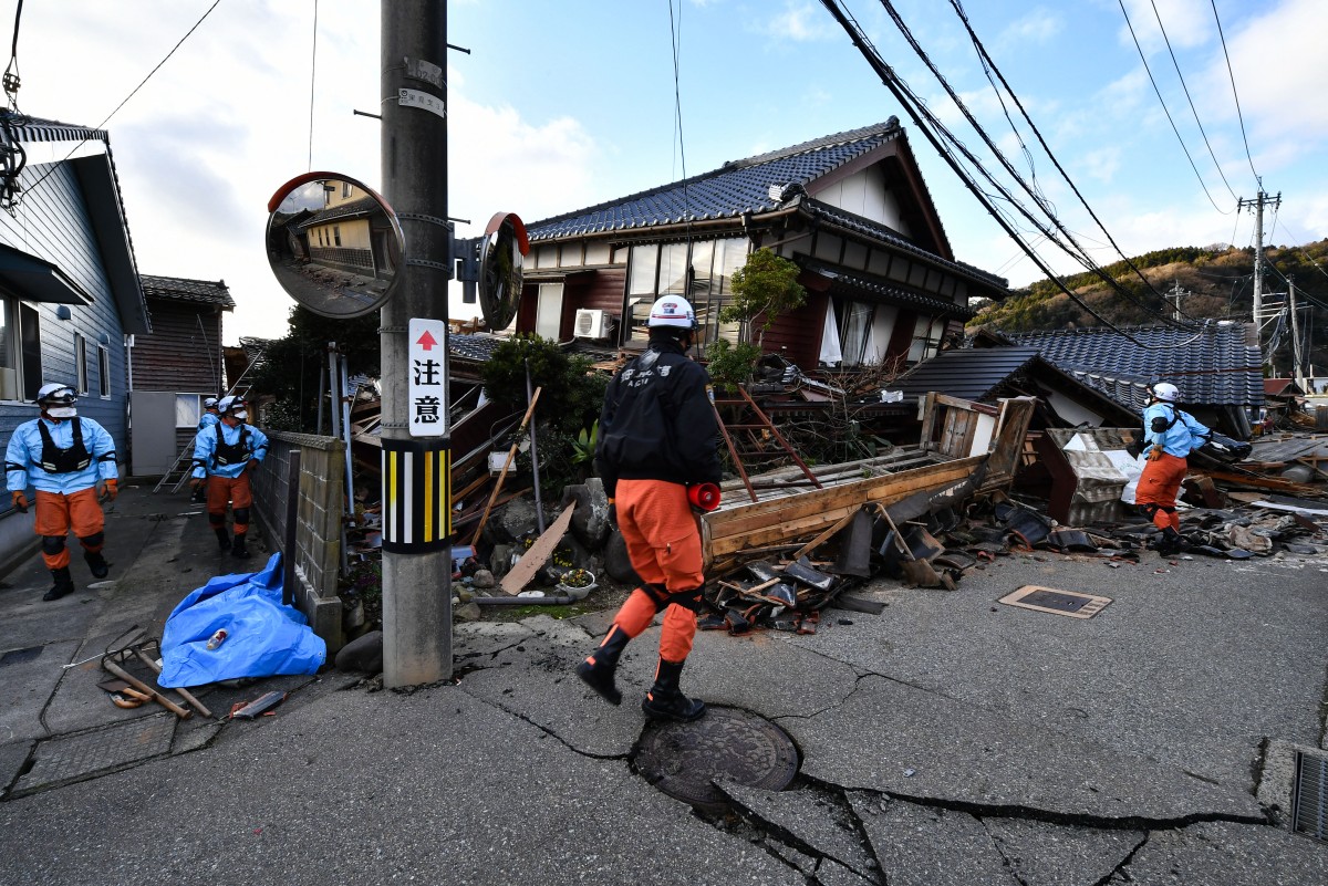 Firefighters inspect collapsed wooden houses in Wajima, Ishikawa prefecture.